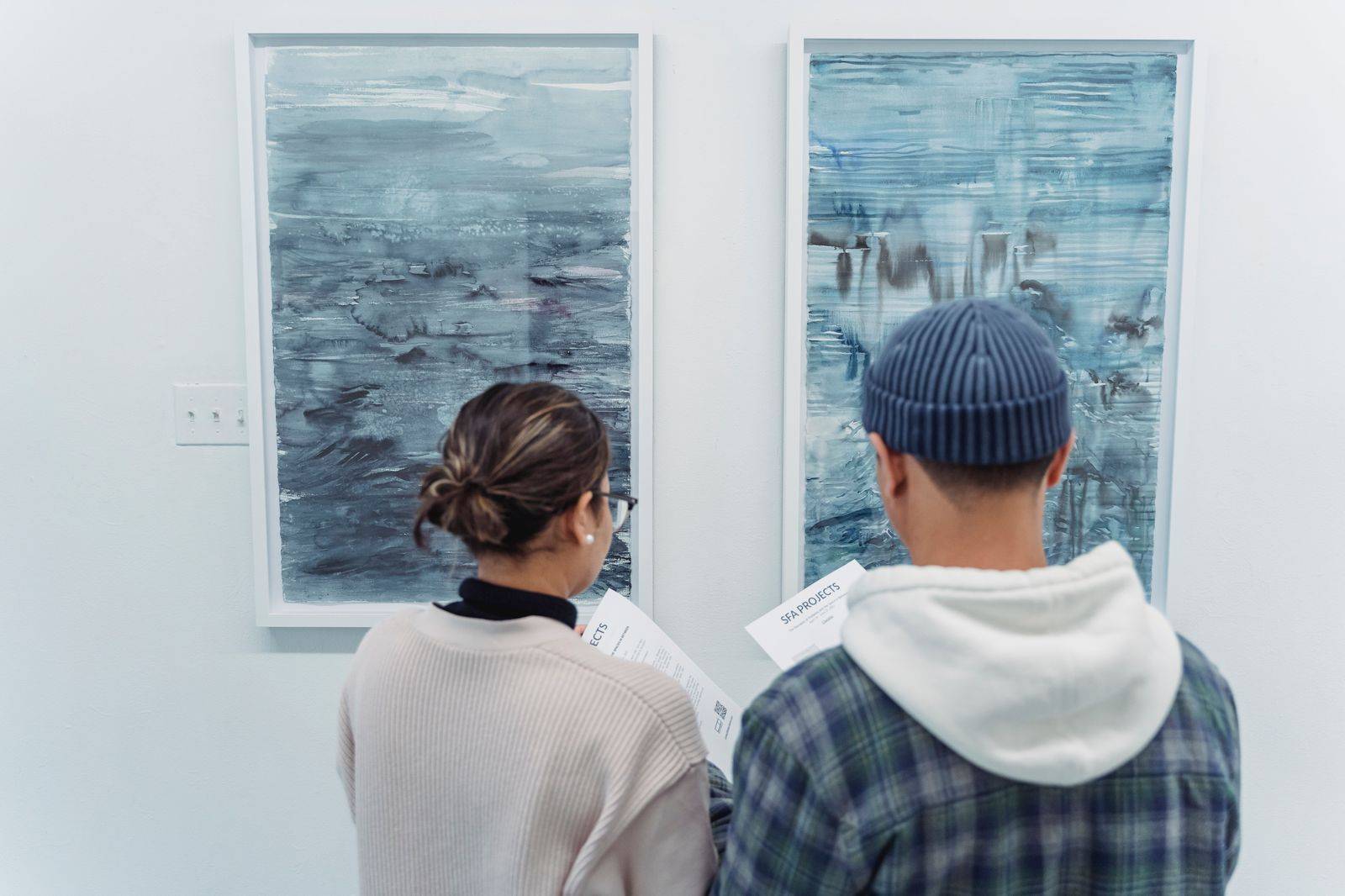Visitors viewing paintings in a bright art gallery room