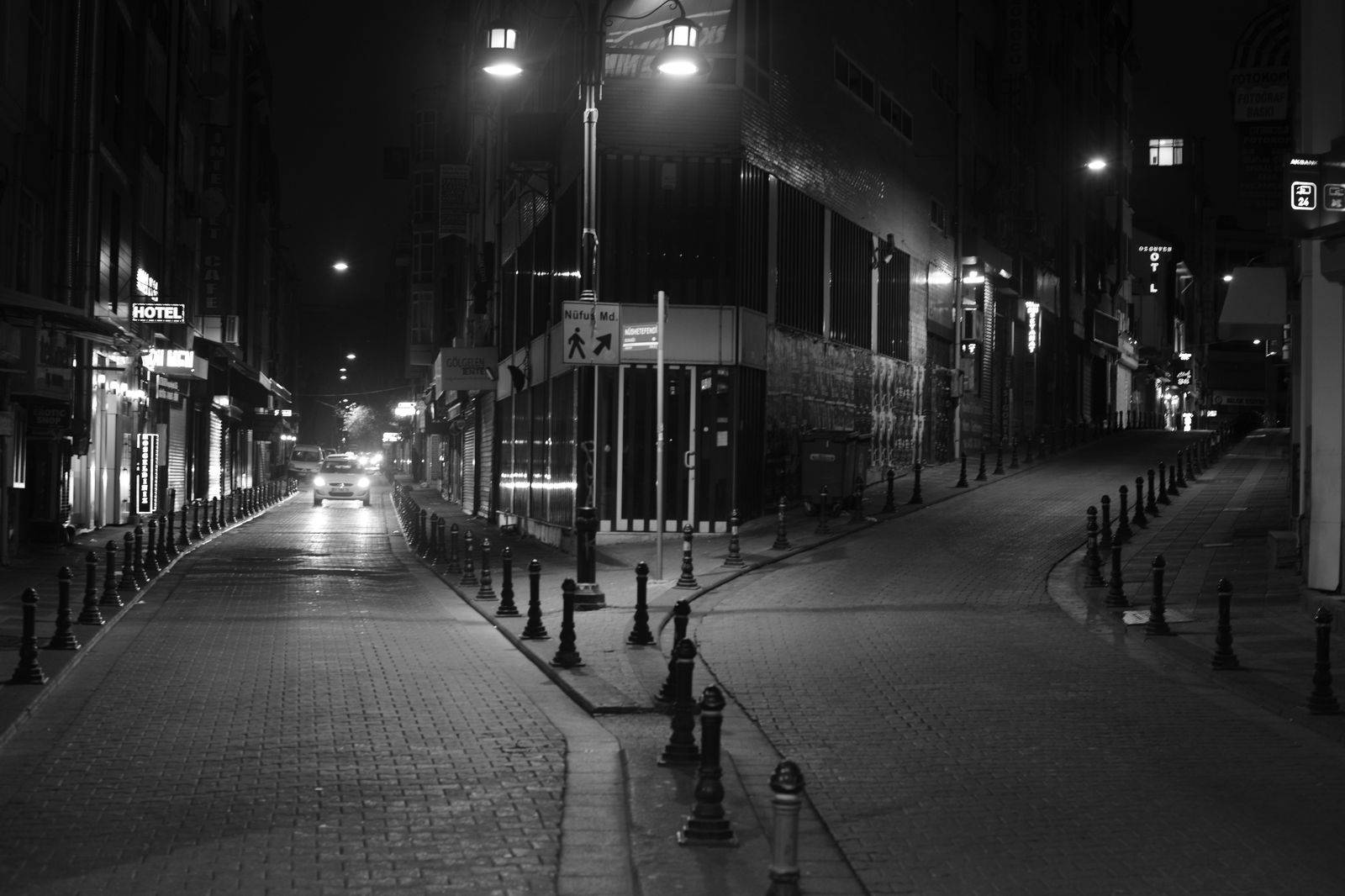 A black sedan waiting on a downtown Toronto street near the CN Tower in the evening