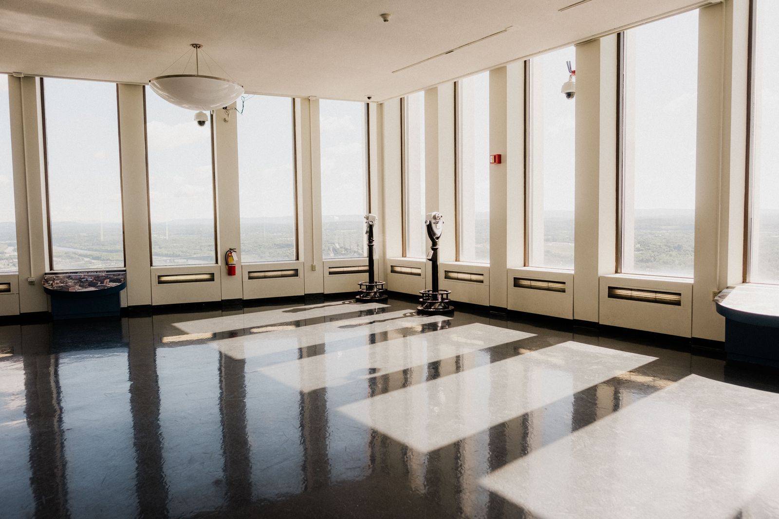 Visitors looking down through the glass floor of an observation deck high above a city