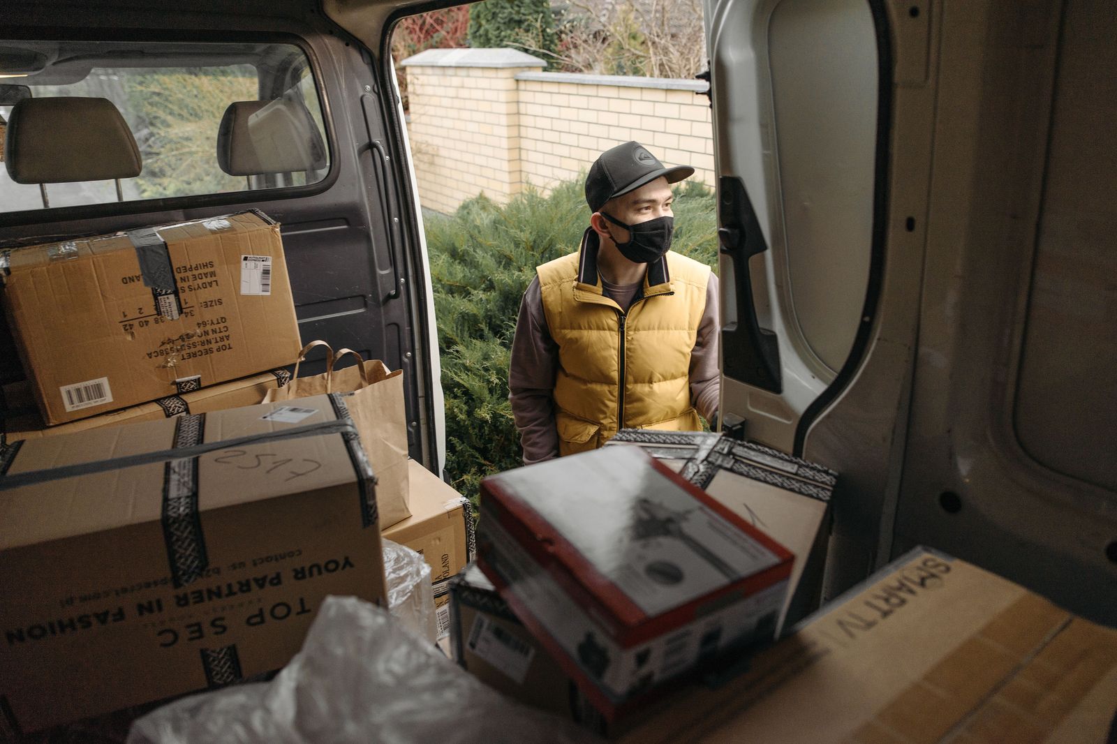 A chauffeur loading shopping bags into the trunk of a black car