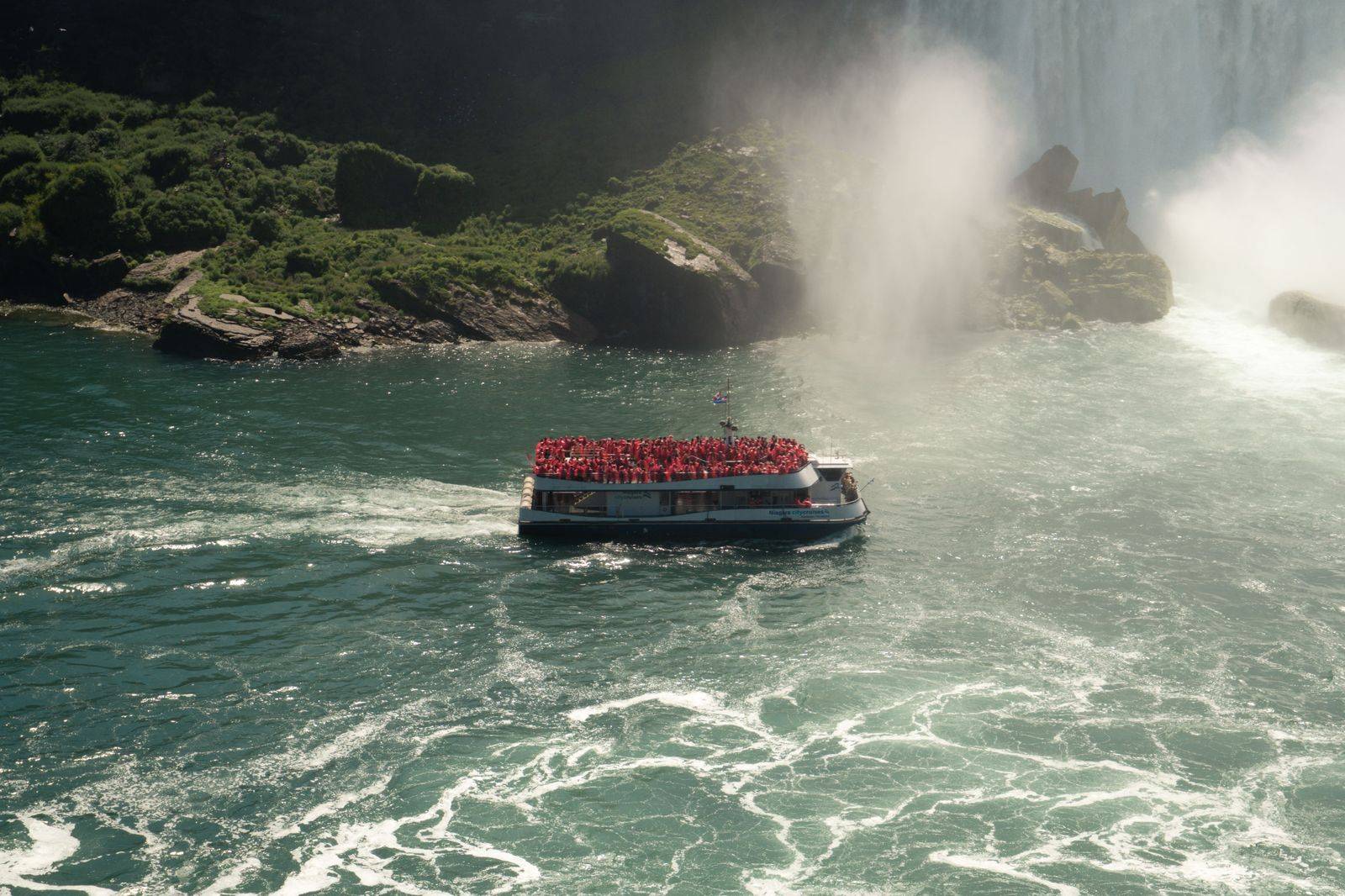 A boat full of passengers in ponchos heading into the mist below the falls, the stop most first-time visitors put at the top of the list