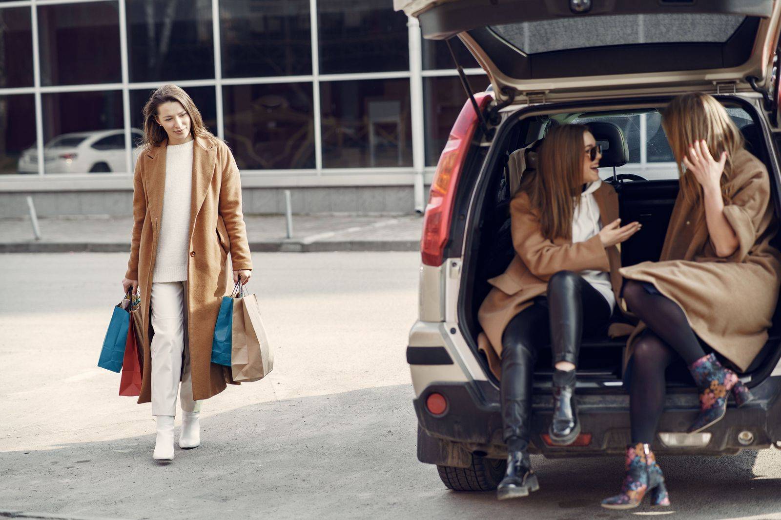 Shopping bags being loaded into the trunk of a black car