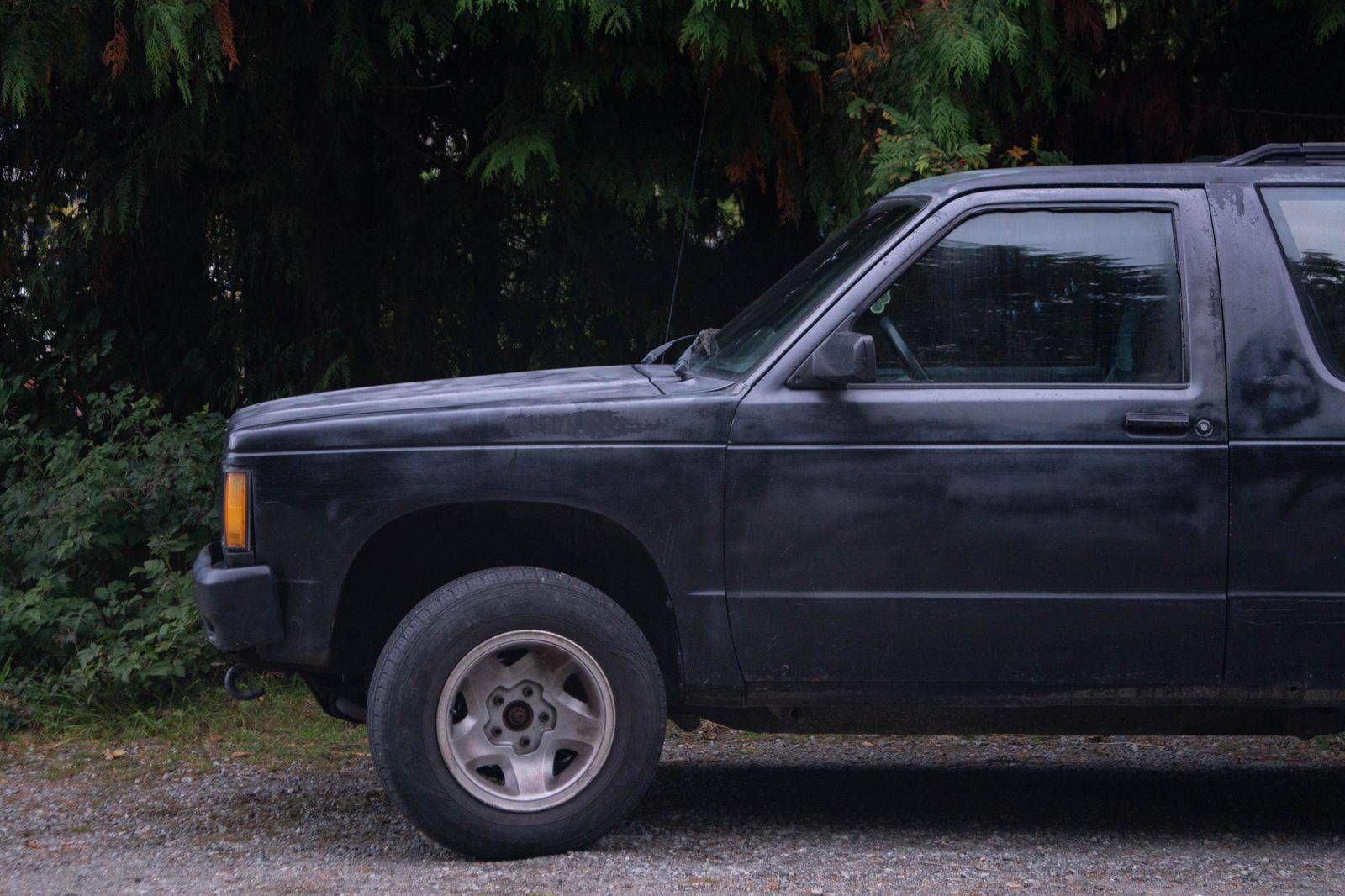A black SUV waiting on a park road at the edge of the Rouge forest for hikers coming off the trail