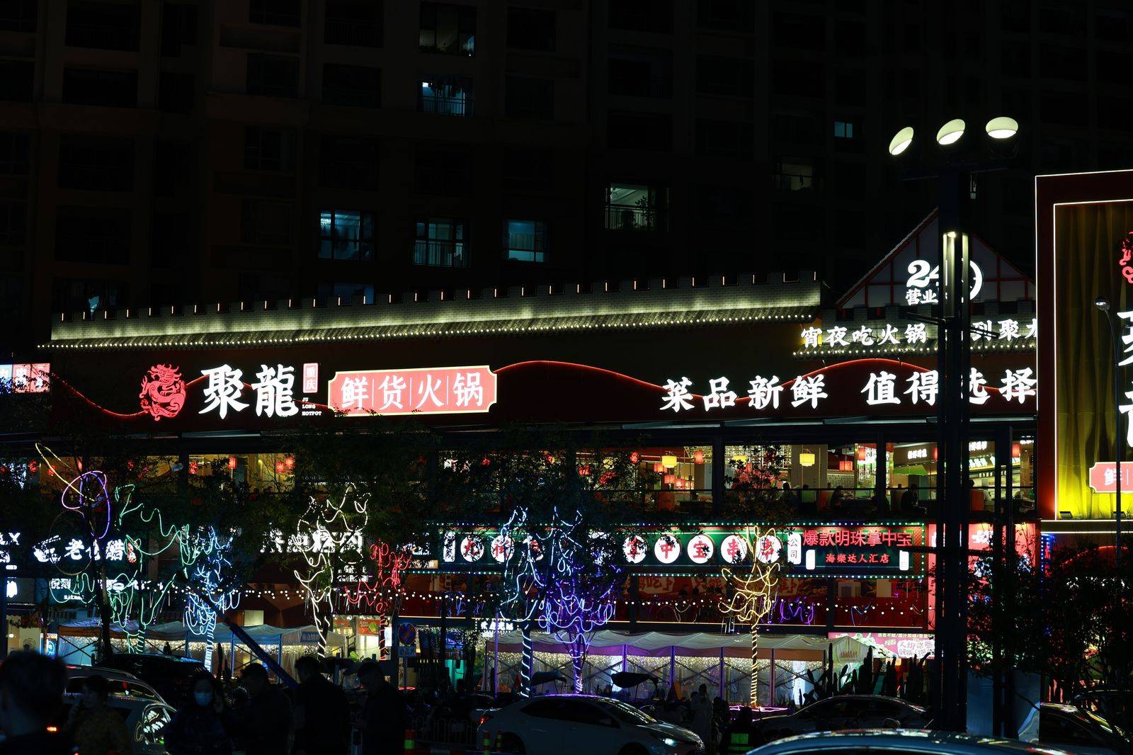 A busy city street at night with restaurant lights and crowds