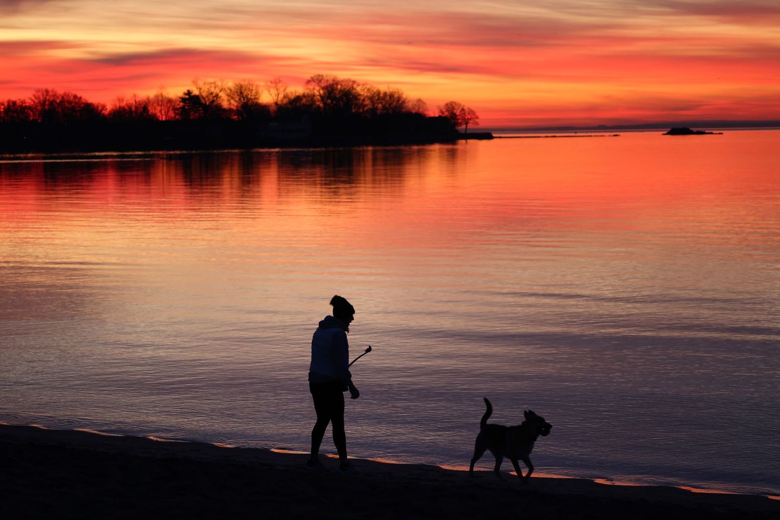 A couple walks along the lakeshore at sunset on a Toronto anniversary evening