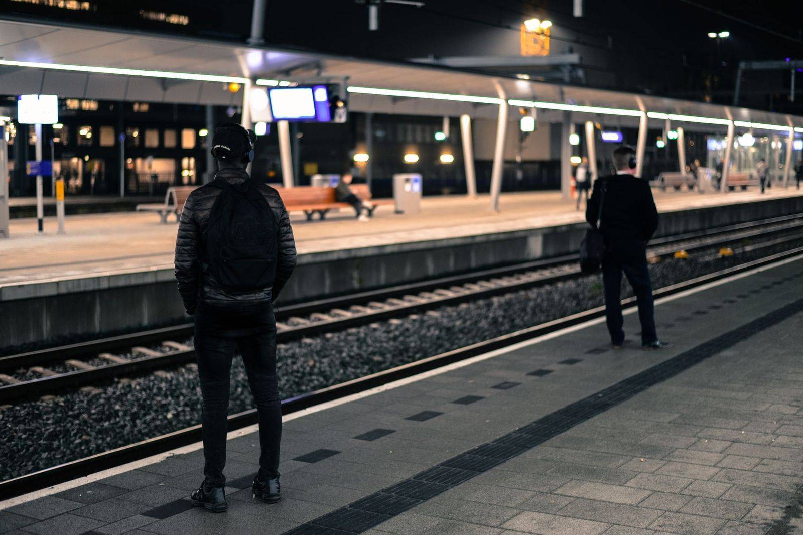 Commuters on a train platform at night in a large city station