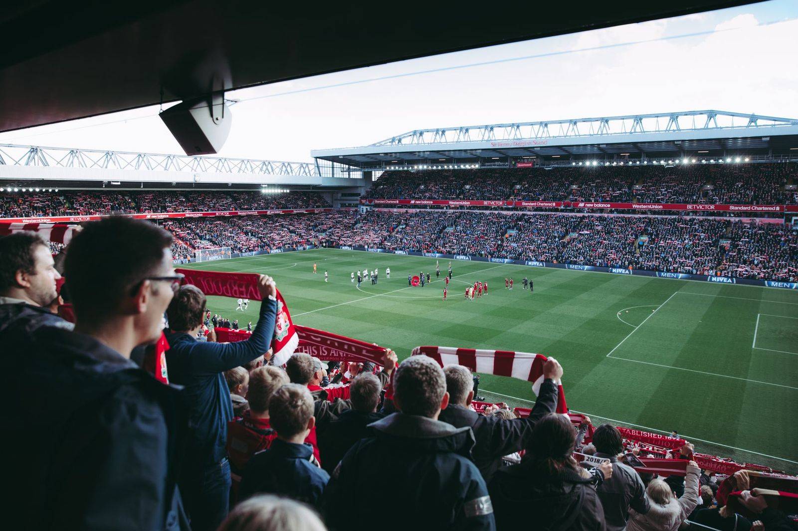 Football fans cheering in an open-air stadium on an evening game day