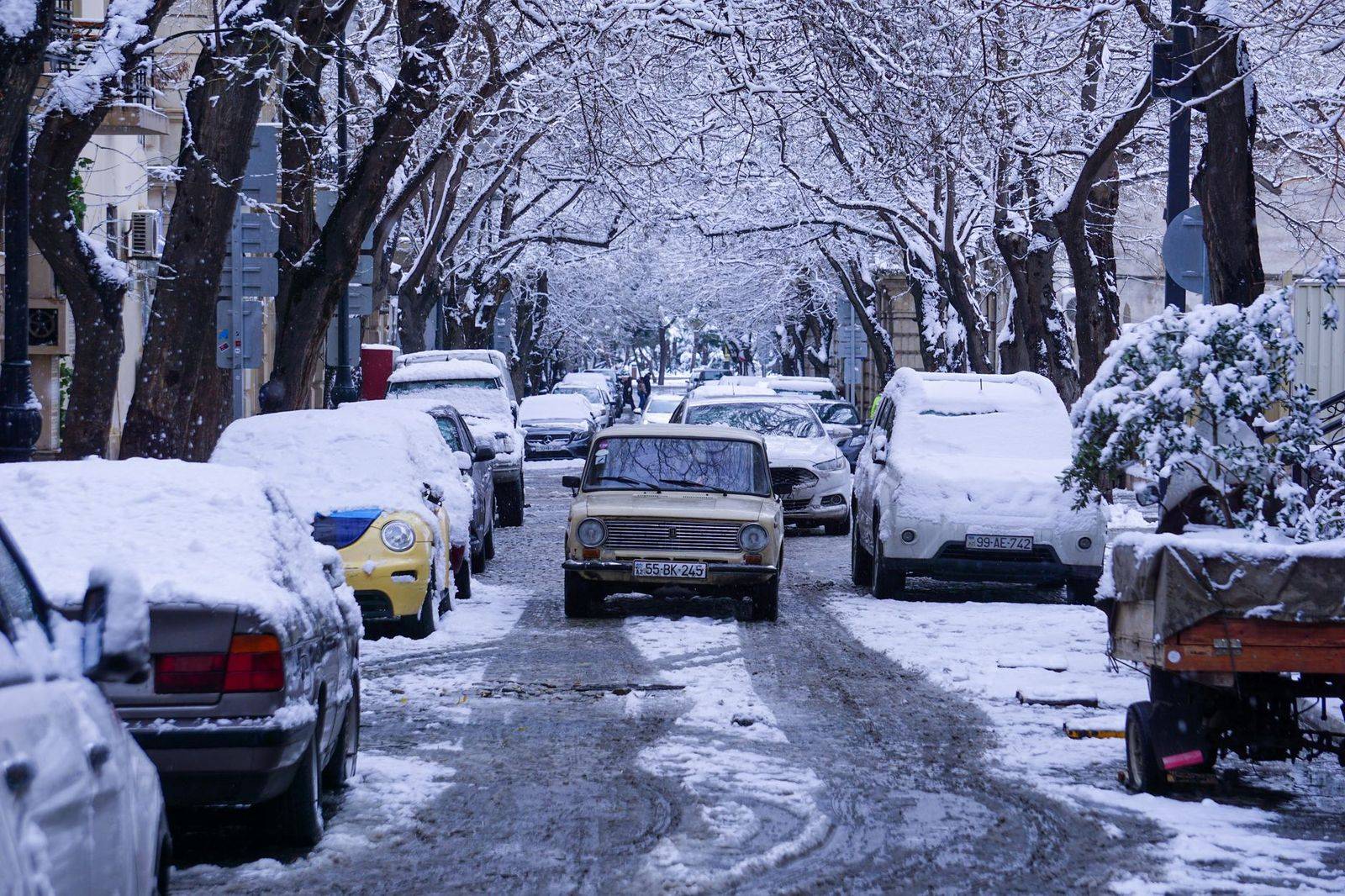 A black sedan on a snowy downtown street