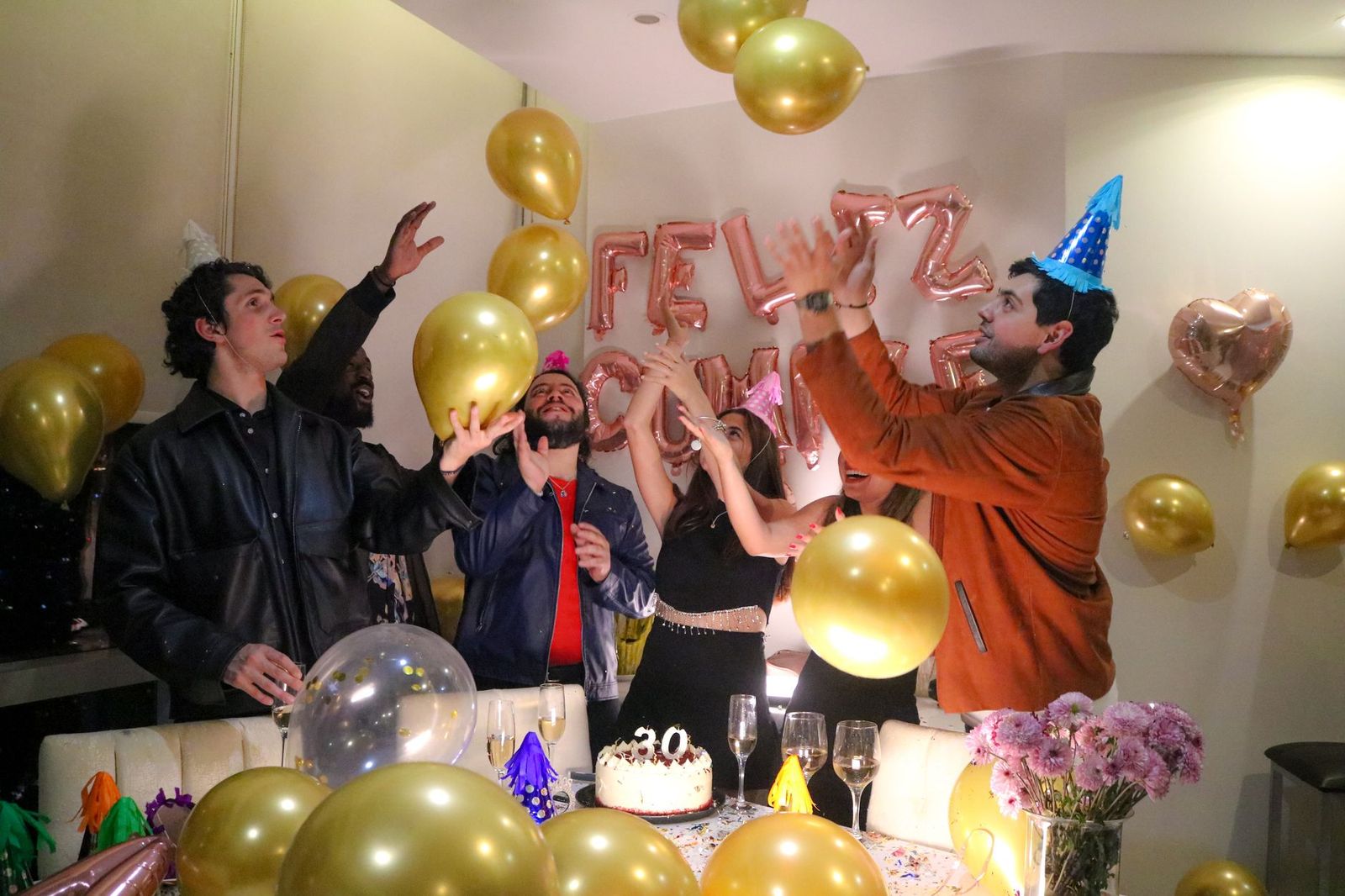 Friends gather around a birthday cake with candles at a restaurant table