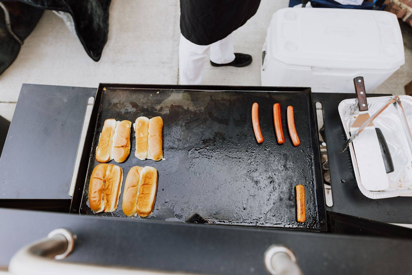 Fans gathered around a grill in a stadium parking lot before a football game