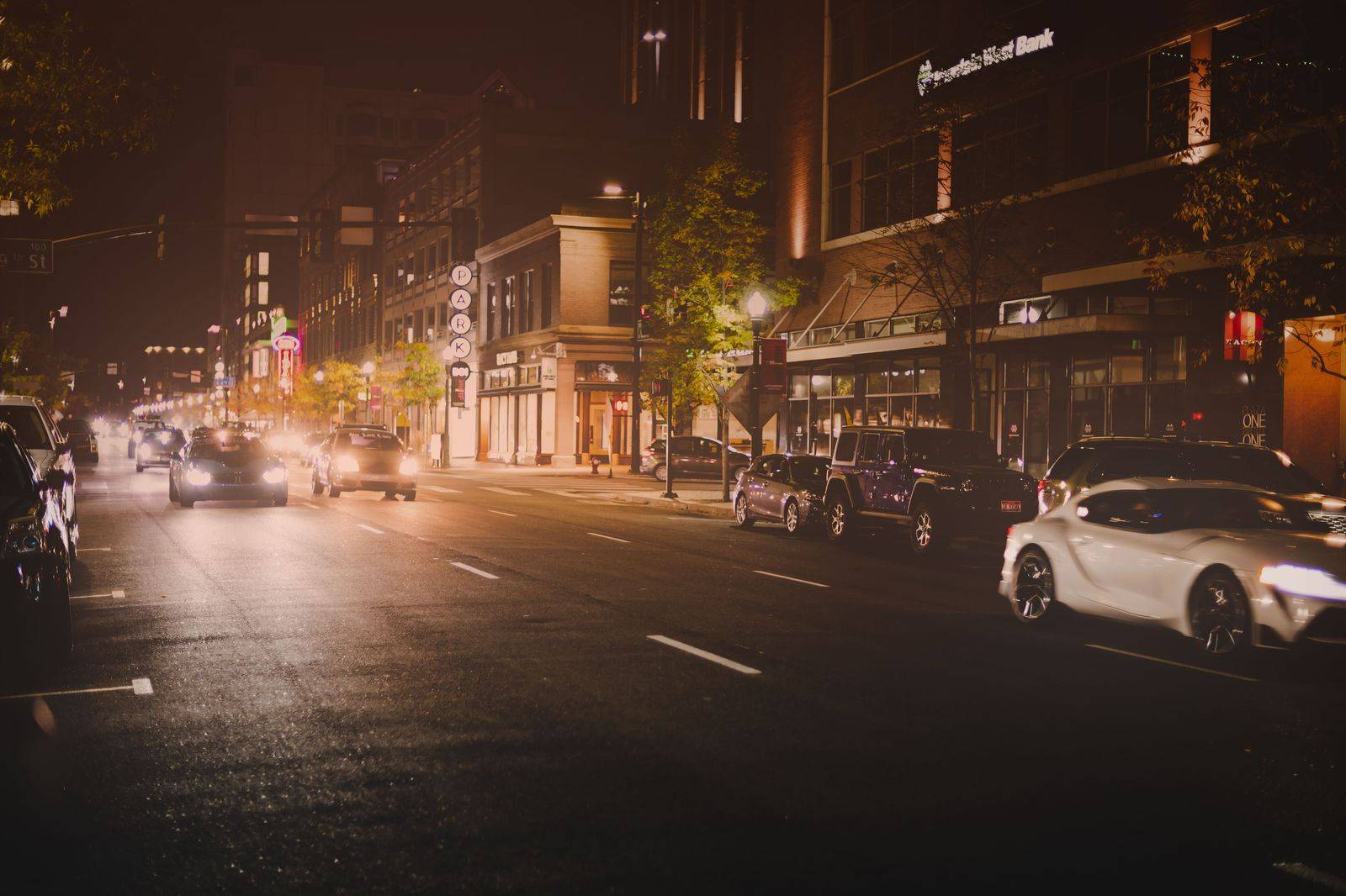 A black car waiting on a downtown street at night