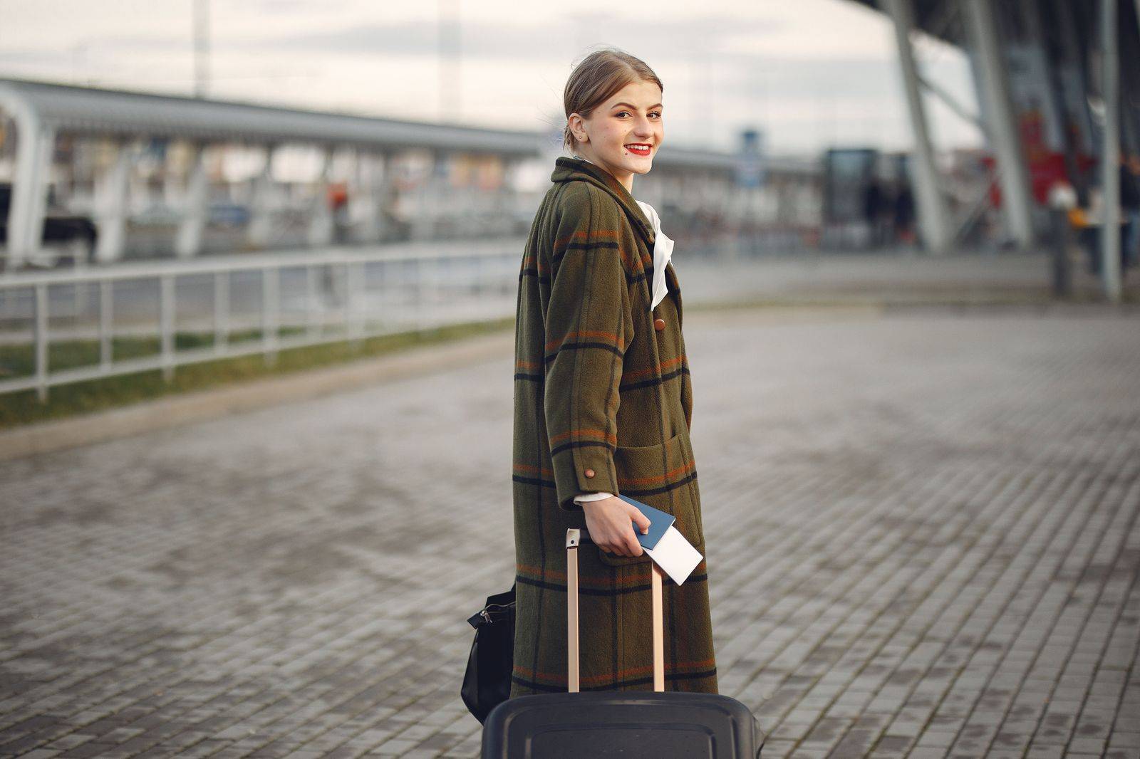 A business traveller with a rolling suitcase heading to a pre-booked car at the airport