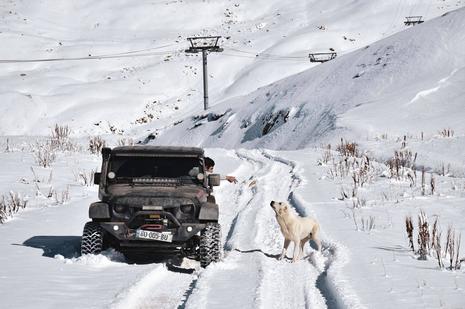 A black SUV driving up a snowy mountain road toward a ski resort