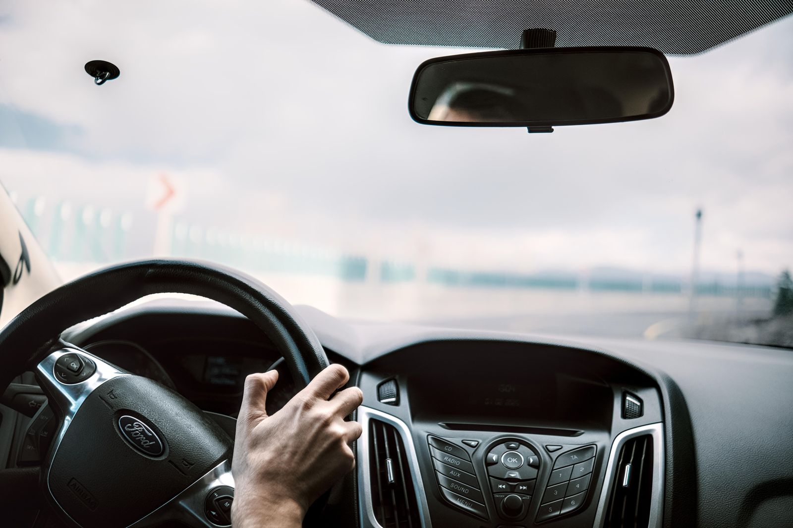 A chauffeur driving a black car on a highway toward the border
