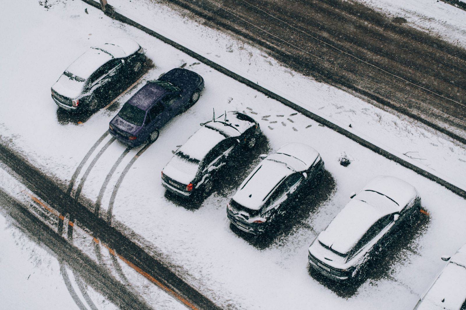 Cars covered in snow in an airport parking lot after a winter storm