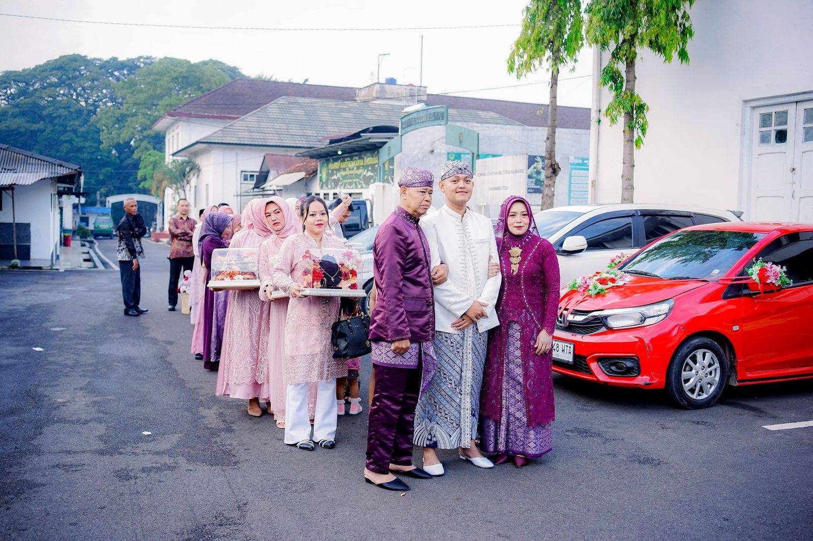 A wedding party gathered beside a black car before the ceremony