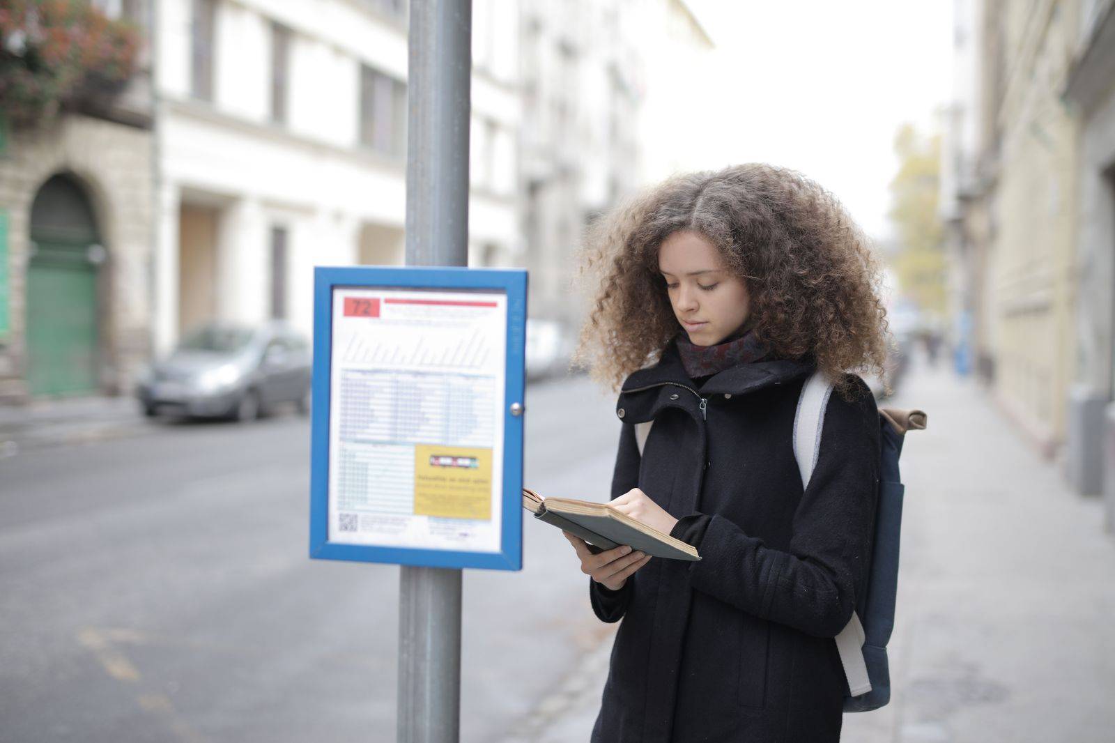 Traveller with a suitcase waiting at a city bus stop on the way to the airport