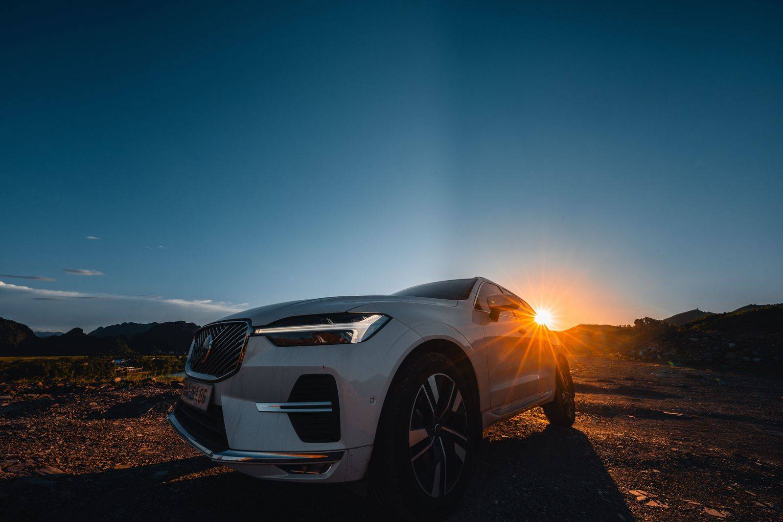Black SUV on a highway through Midwest farmland at sunset