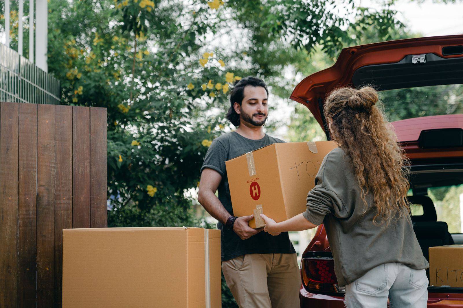 A family unloading bags and a cooler from a black SUV beside a lakeside cottage