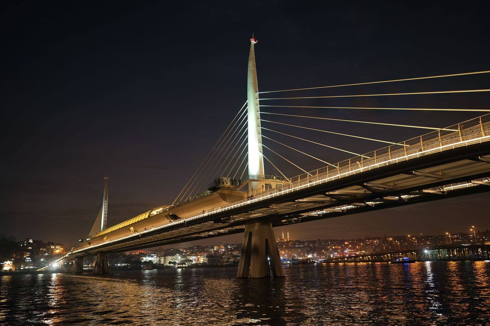 Cable-stayed bridge lit at night over a river crossing between Windsor and Detroit