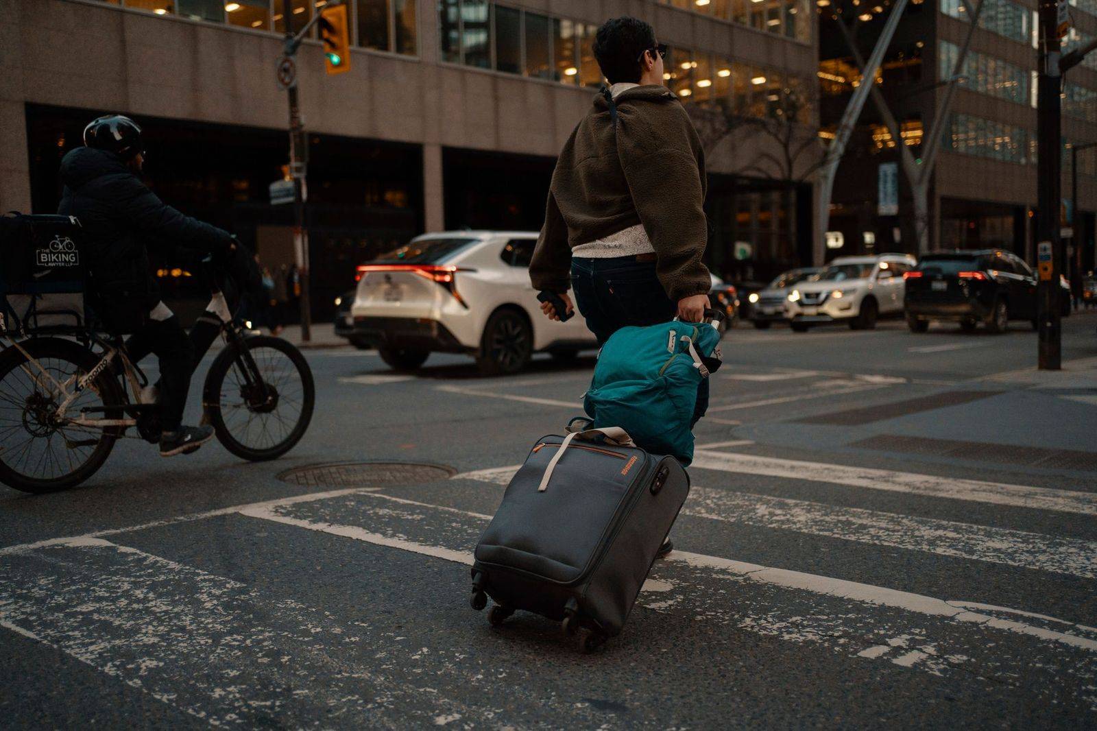 A chauffeur loading suitcases into the back of a black SUV outside a hotel
