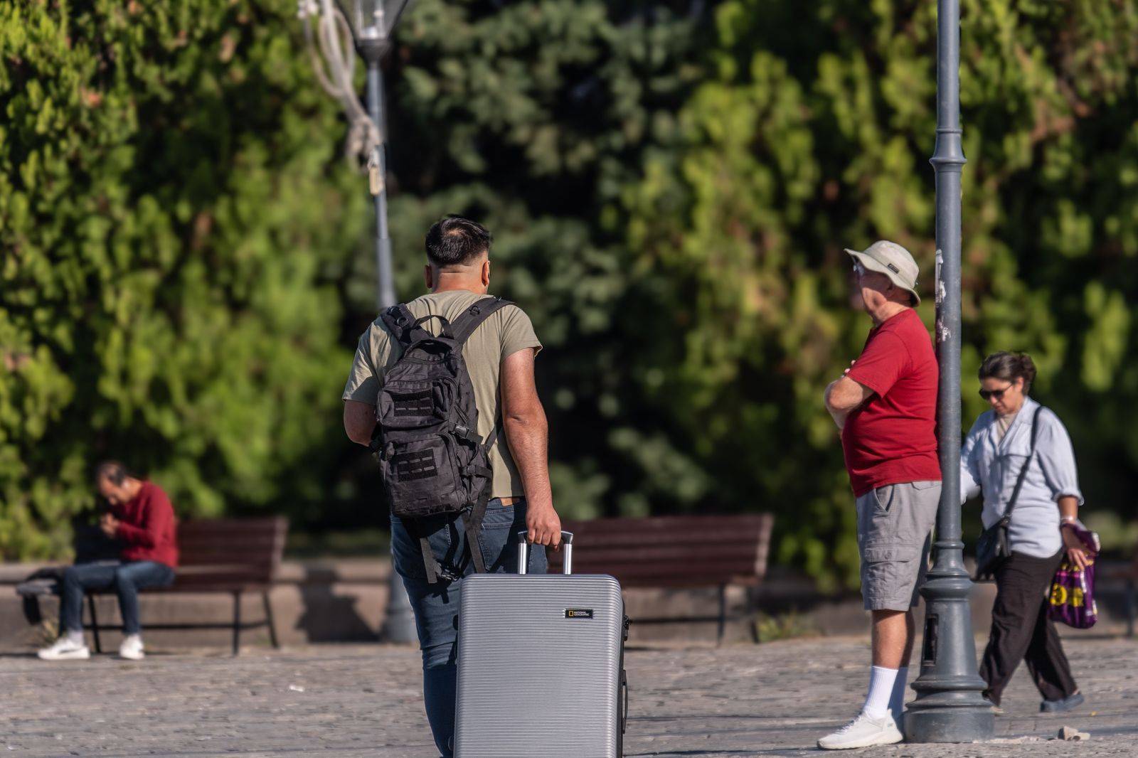 A chauffeur loading a suitcase into the trunk of a black sedan
