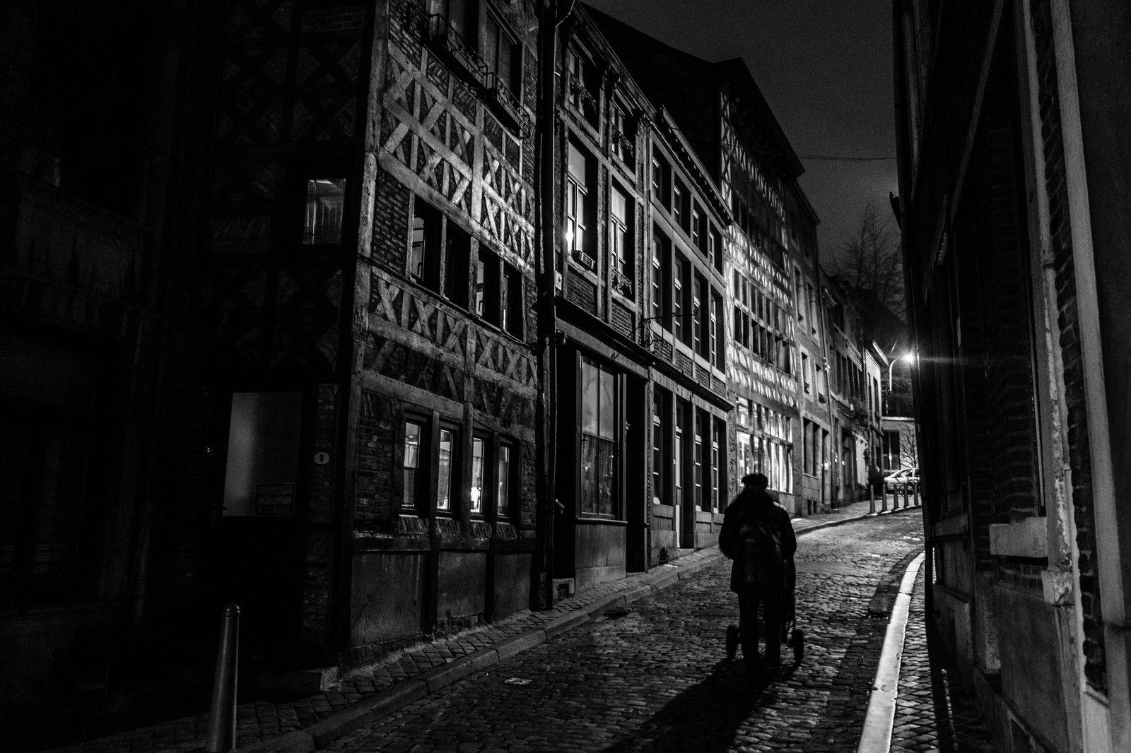 A black sedan waiting on a narrow city street at night