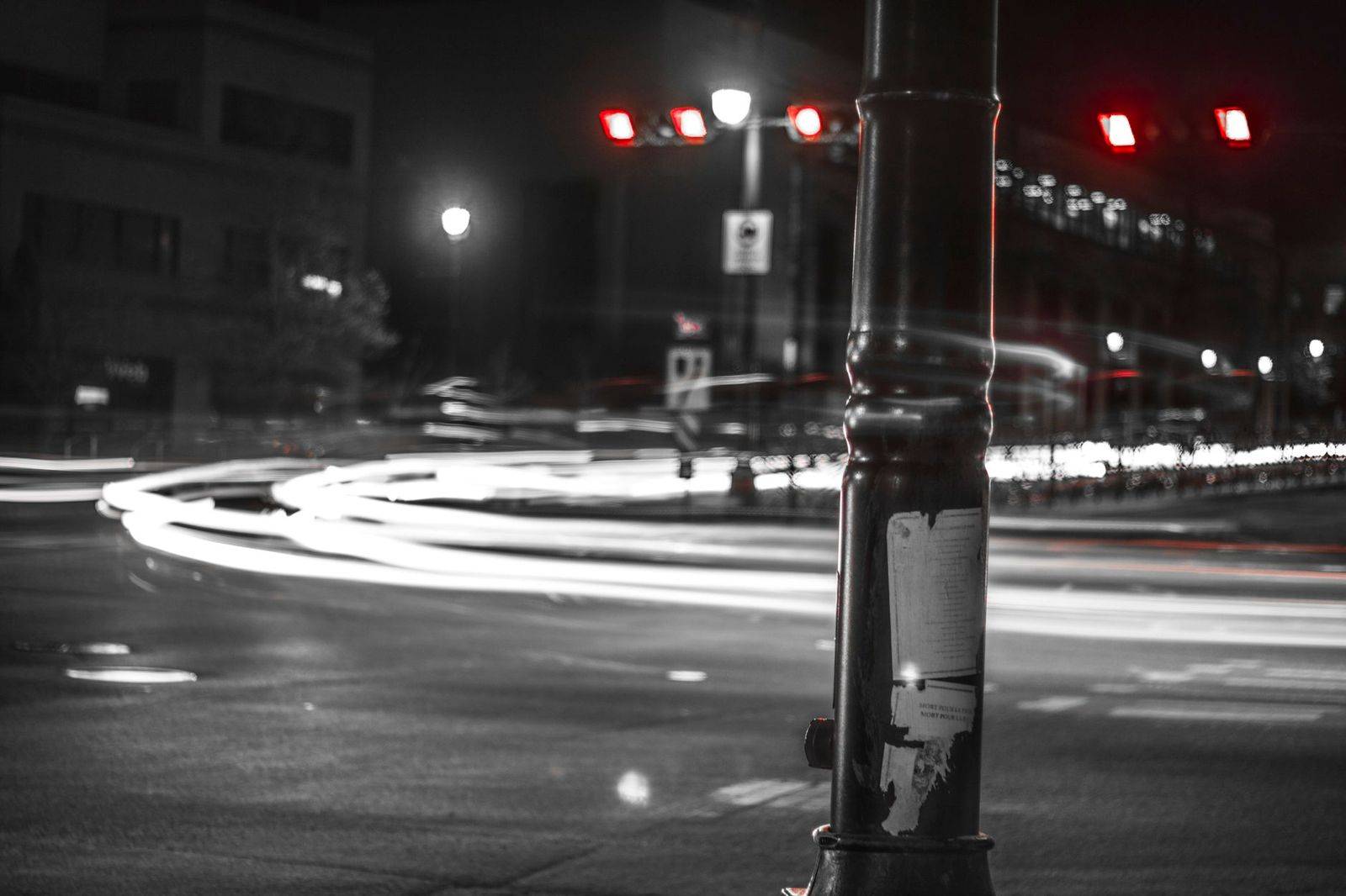 A black sedan waiting on a downtown street under city lights on a winter night