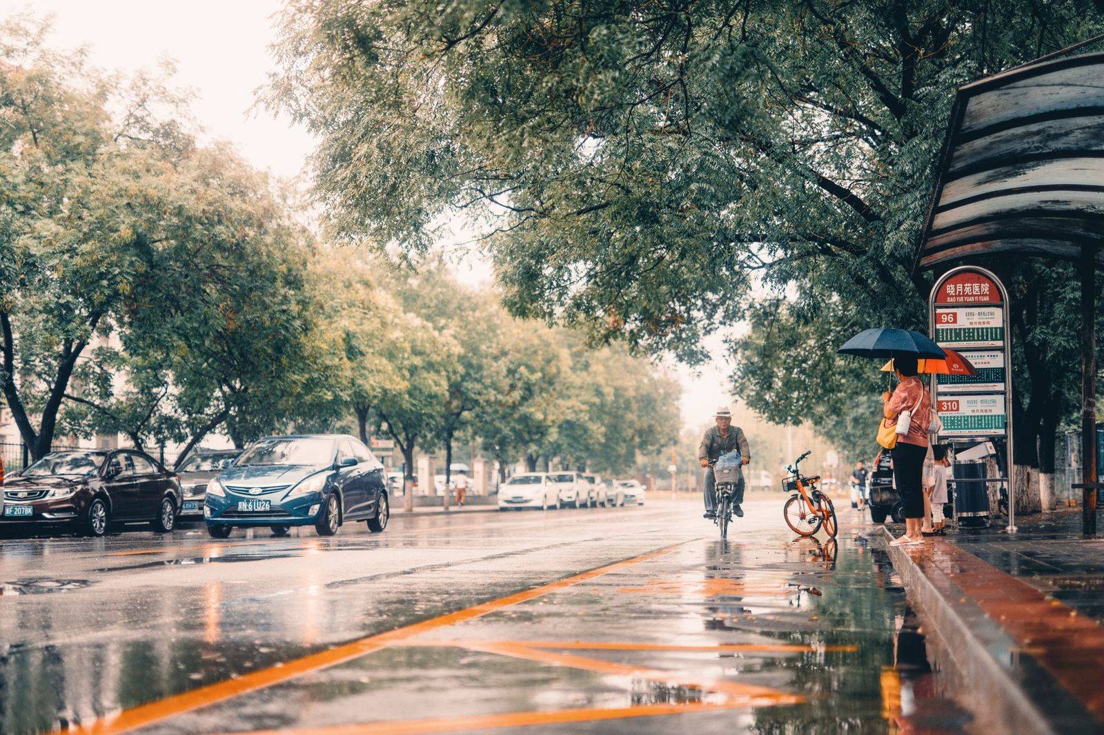 A black sedan waiting on a wet downtown Toronto street after a show