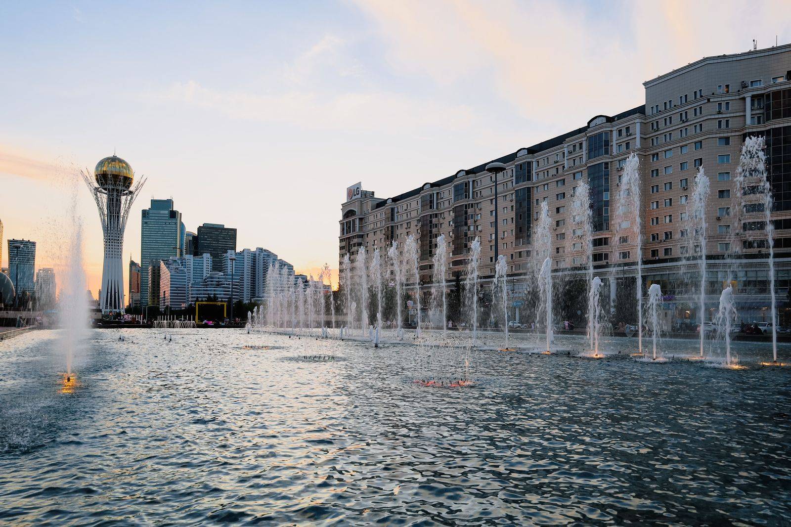 A civic square with a fountain and modern towers