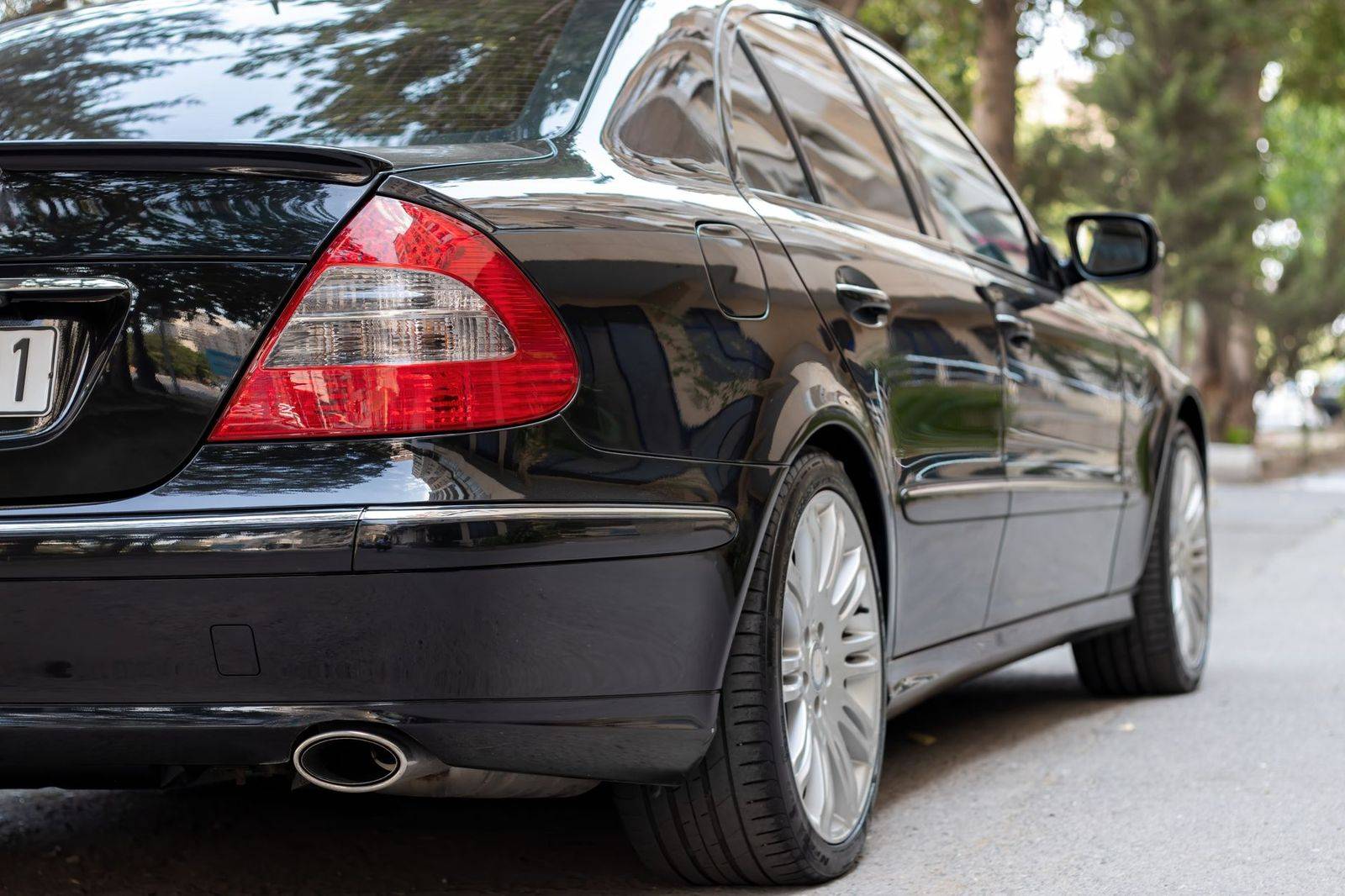 A chauffeur opening the rear door of a black sedan outside a downtown Montreal hotel