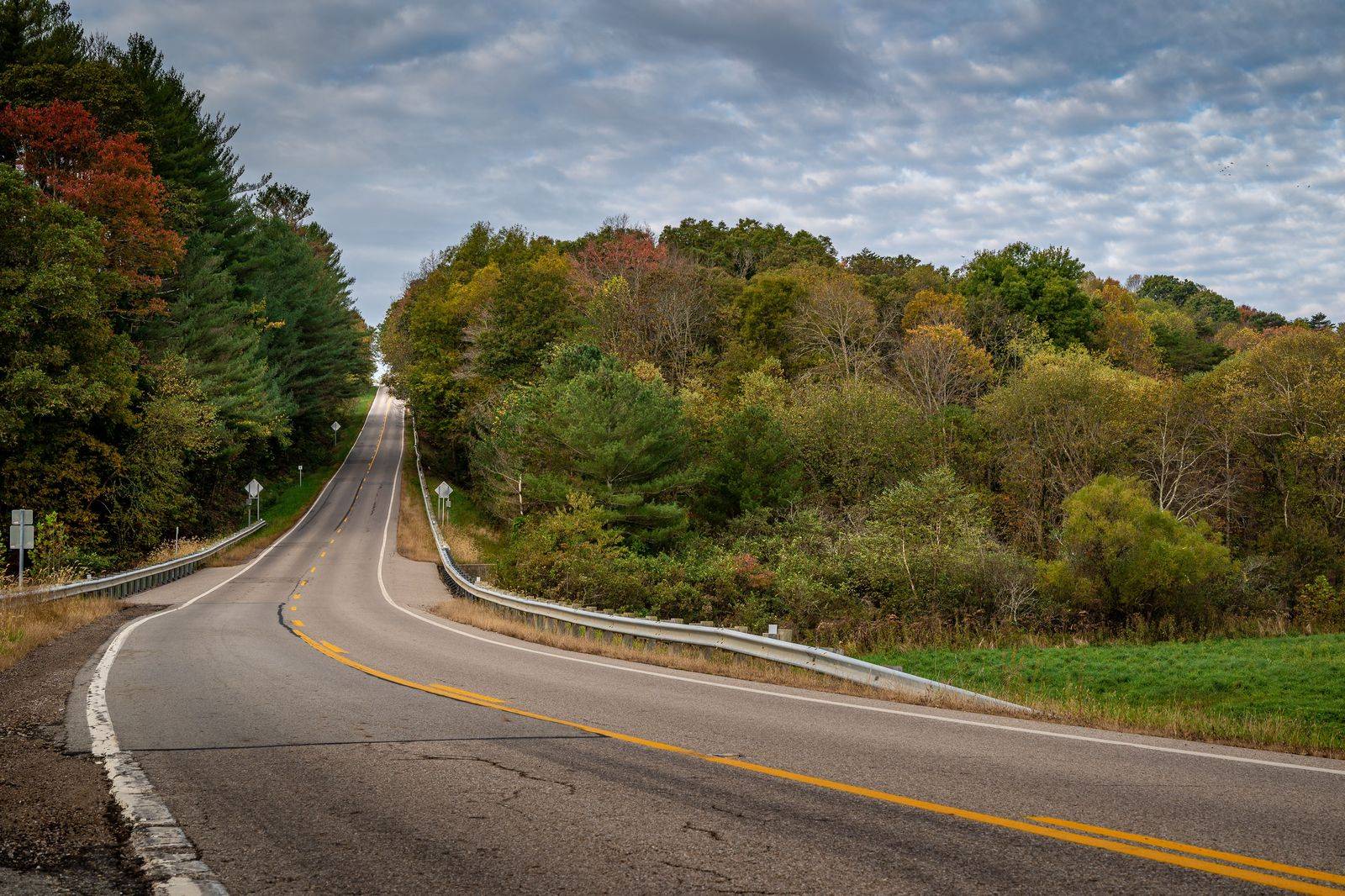 A two-lane highway through a Canadian Shield rock cut beside a lake, typical of Highway 7 east of Kaladar