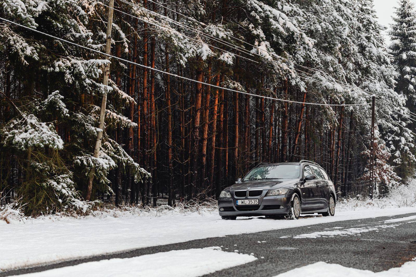 A black car driving on a snowy rural highway, typical of Highway 10 in winter