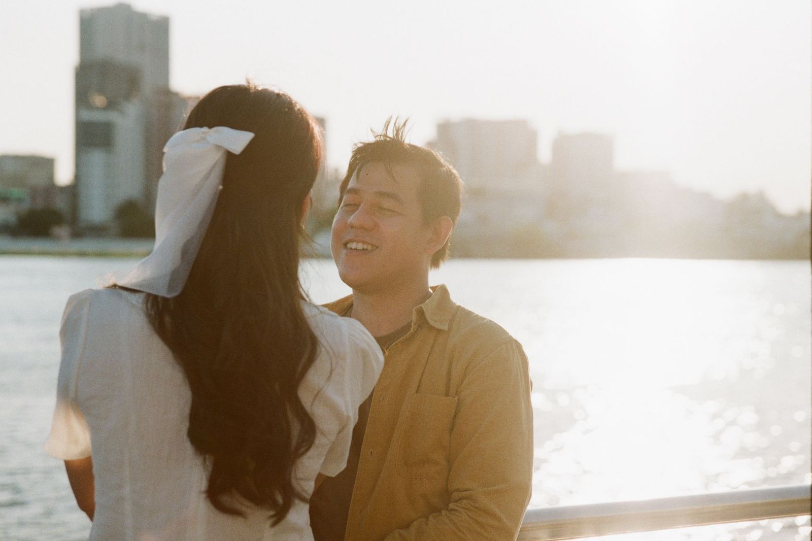 A couple embracing on the waterfront with the Toronto skyline behind them after a proposal