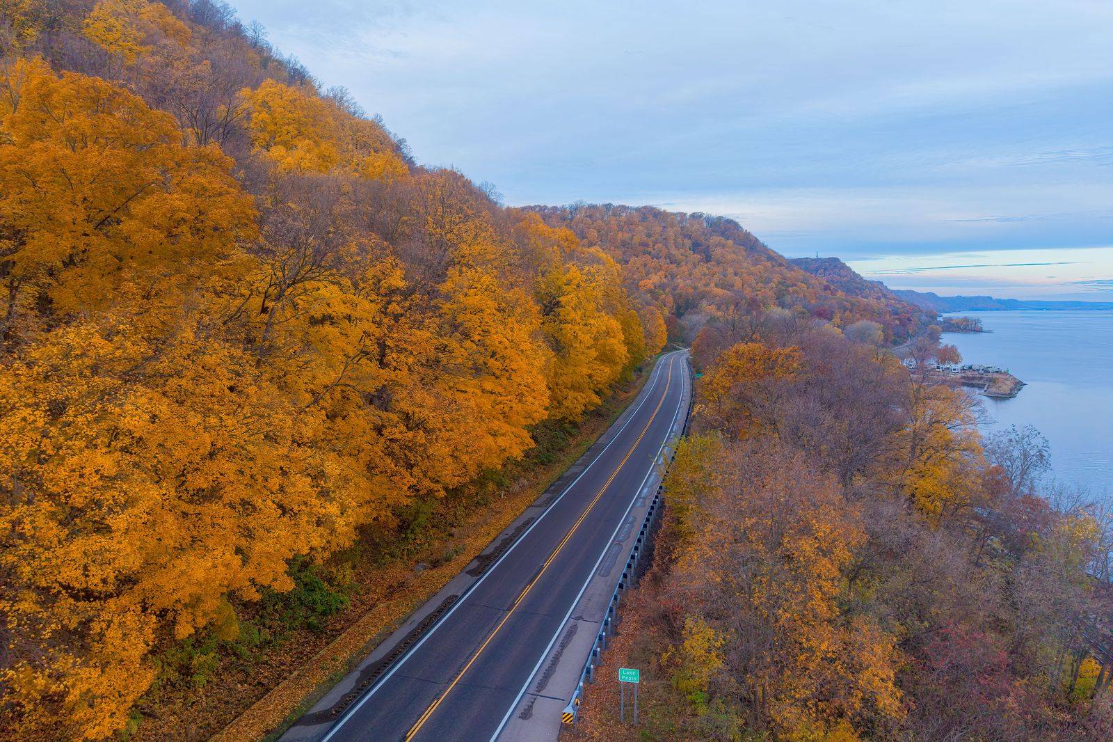 A divided highway running beside a river valley in autumn colour