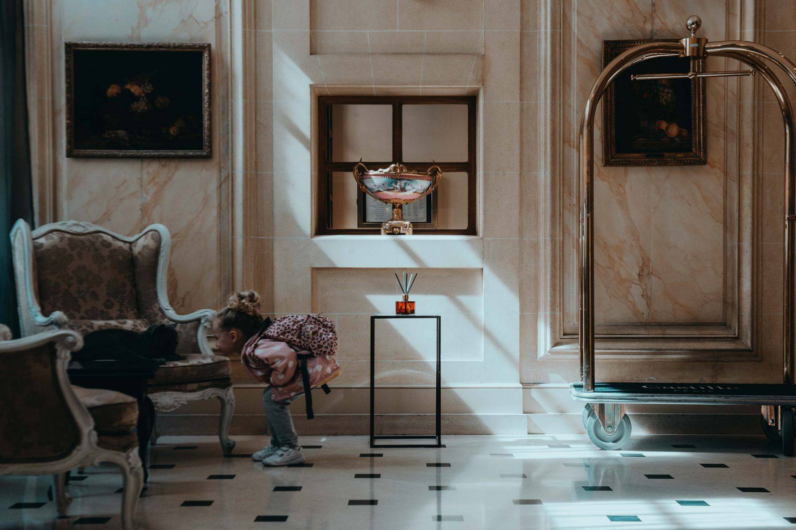 A hotel lobby with a luggage cart and suitcases in the evening