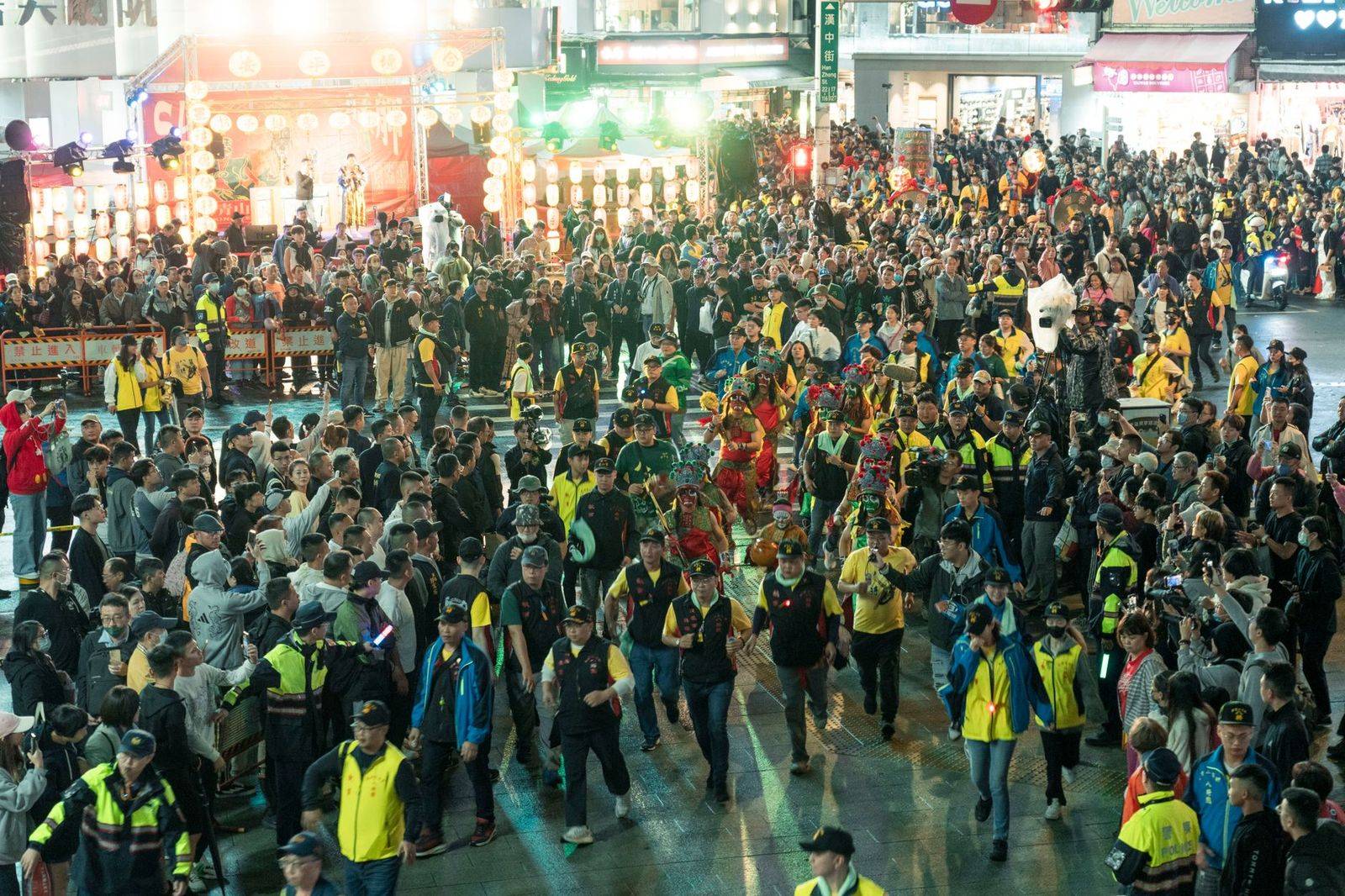 Concert-goers streaming out of a downtown stadium onto a busy street at night