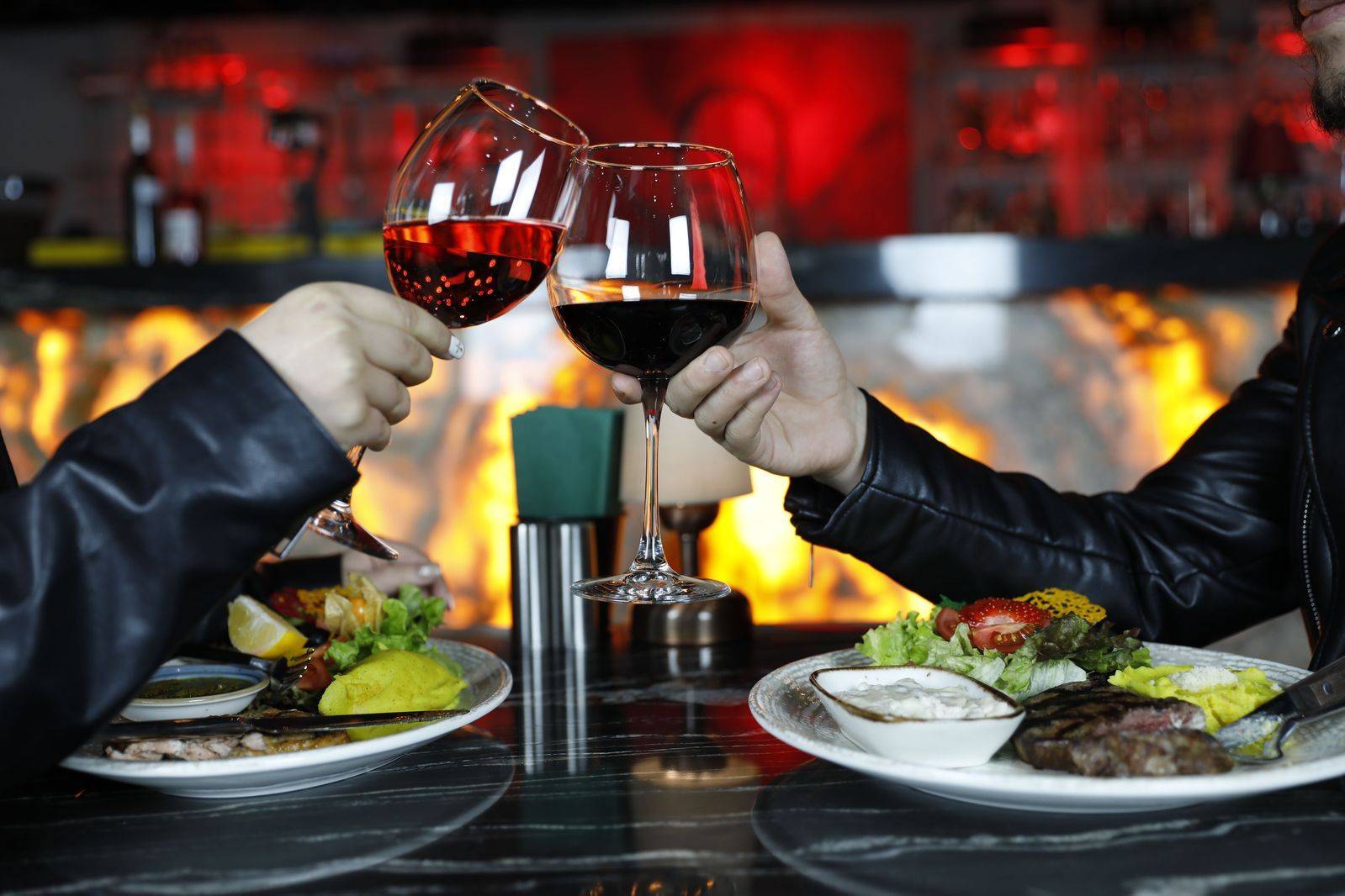 A couple raising glasses at a window table, the centrepiece of a chauffeured anniversary dinner in Toronto