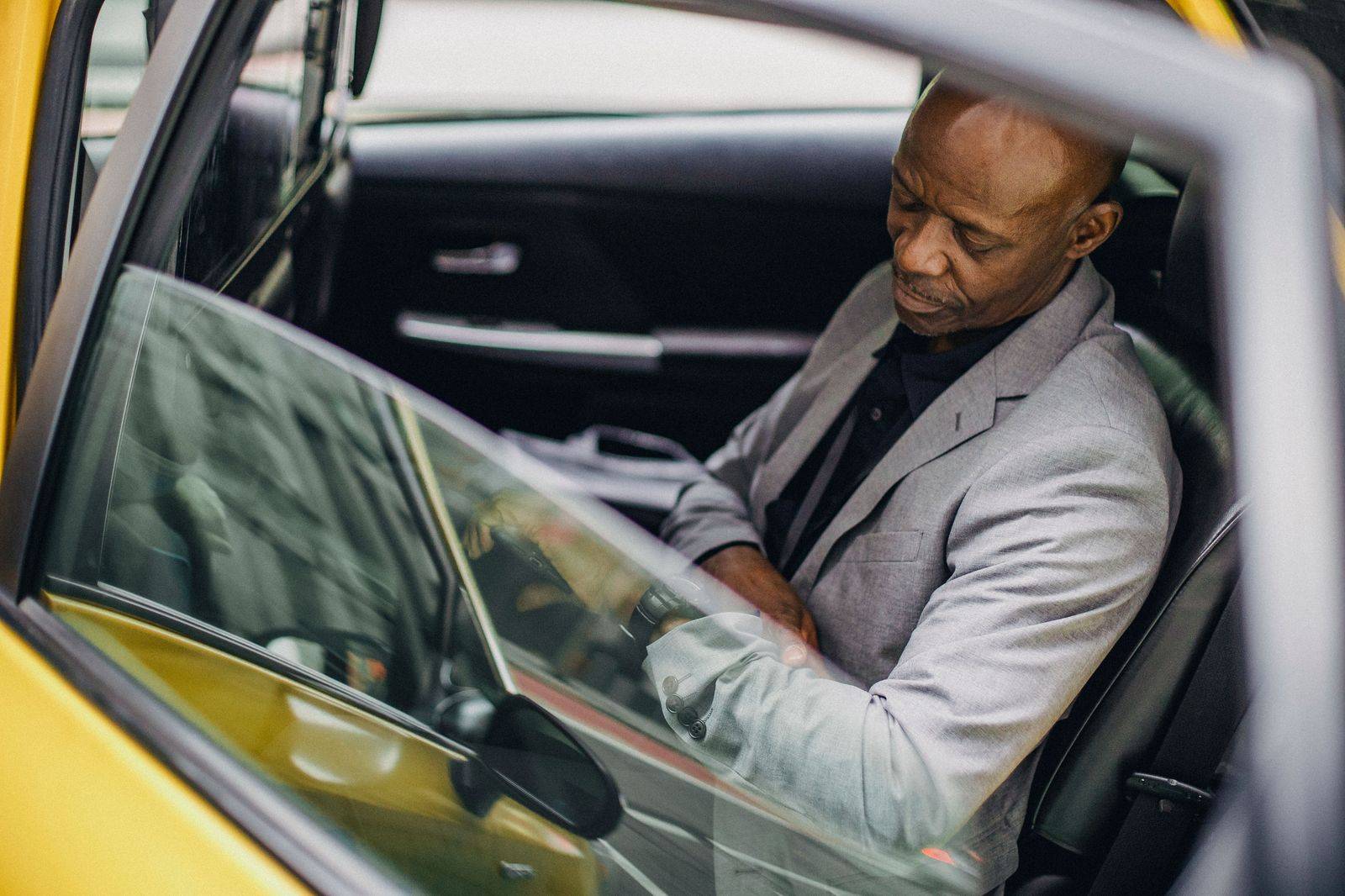 A chauffeur checking the time beside a car during a wait-and-return booking