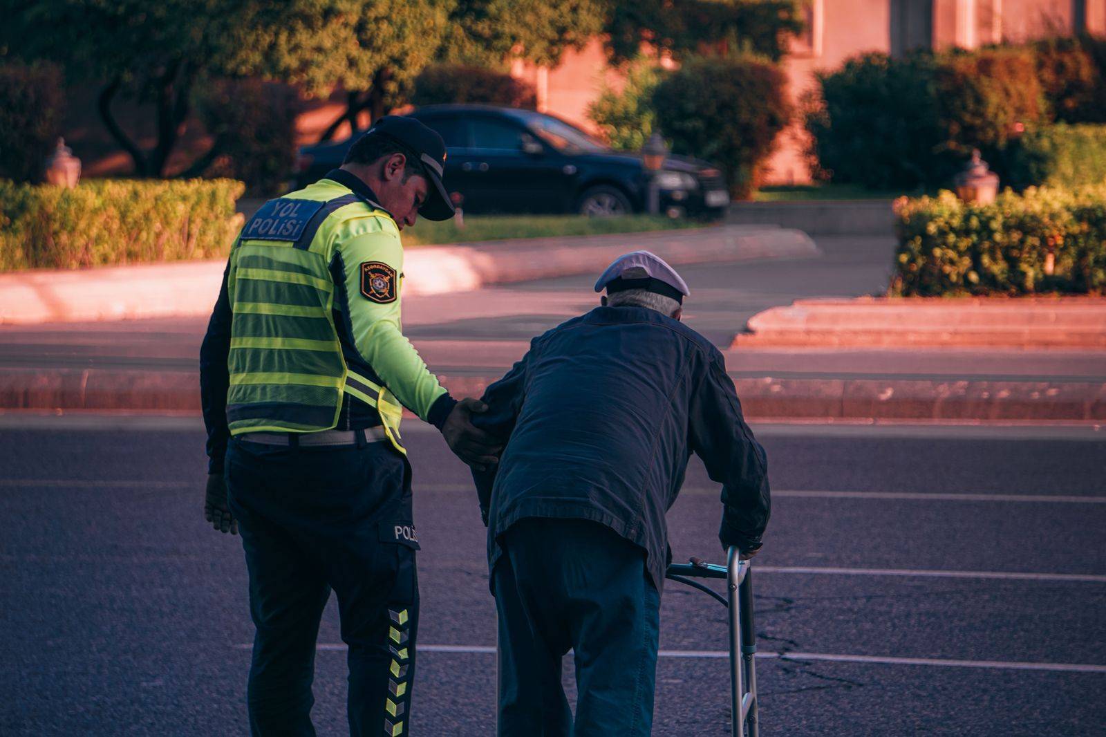 Chauffeur offering an arm to an older passenger stepping out of a black car at a hospital entrance