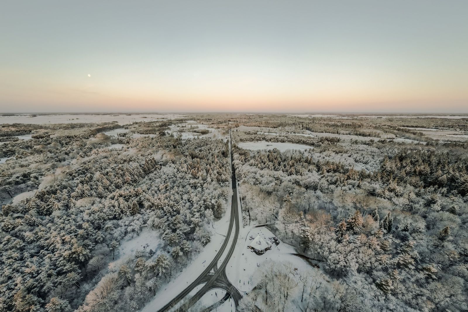 A snowy two-lane road winding through a winter forest