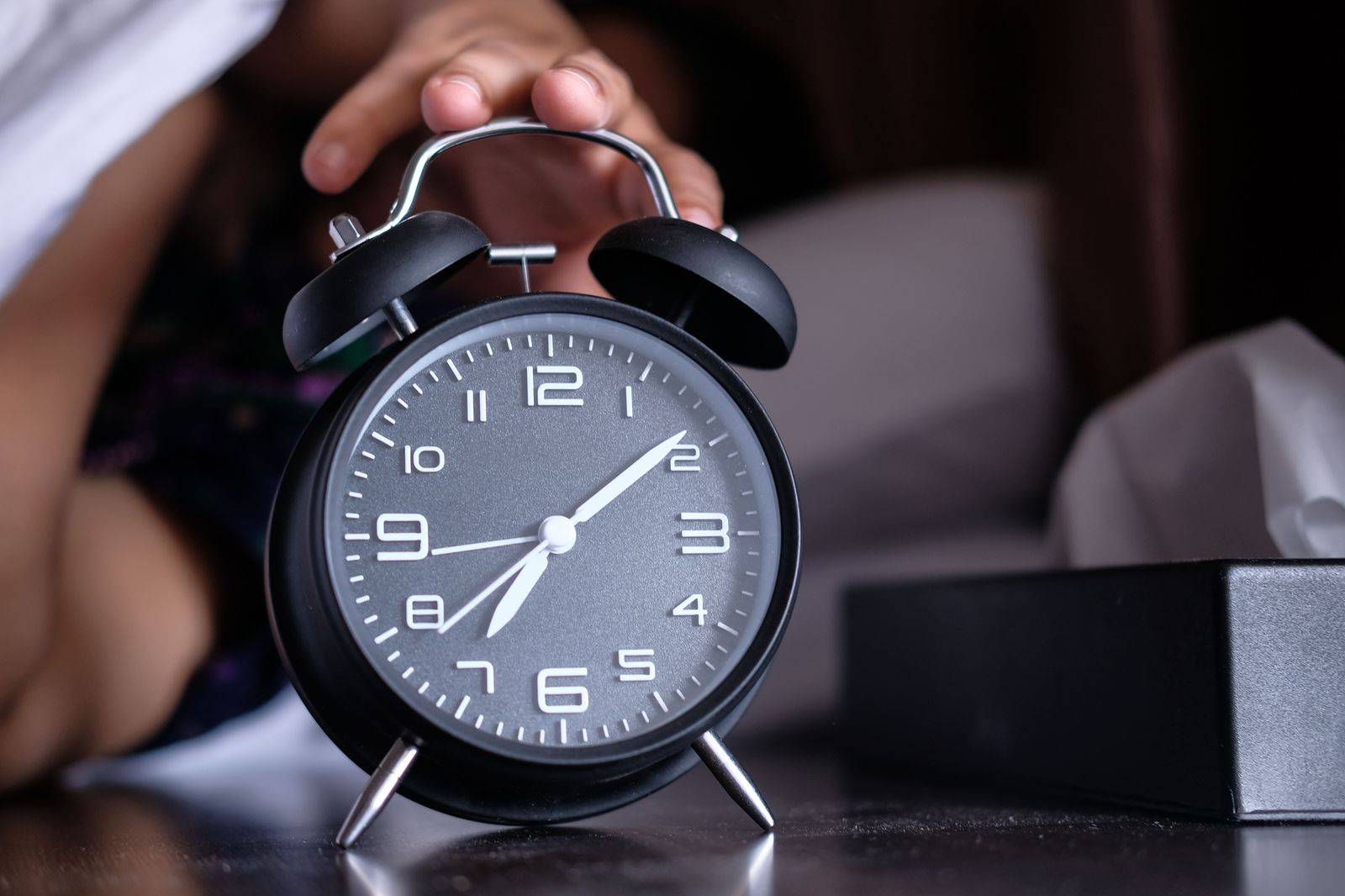 An alarm clock showing the small hours on a bedside table before an early flight