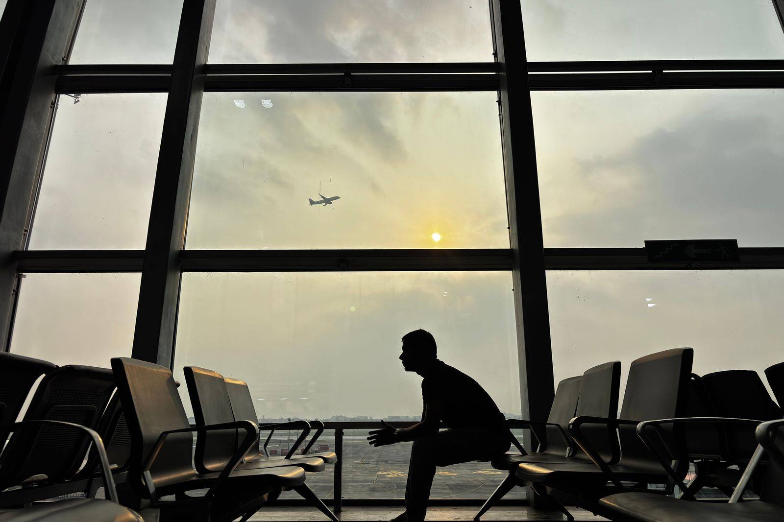 A black sedan at the departures curb of an airport terminal before dawn