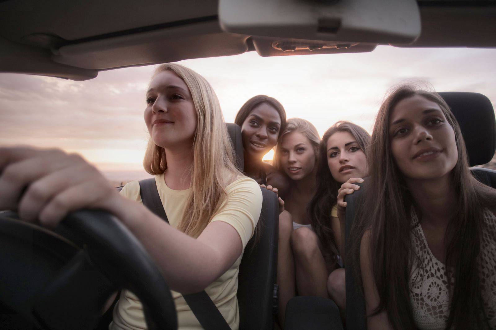 Friends laughing together in the back seat of a car at night