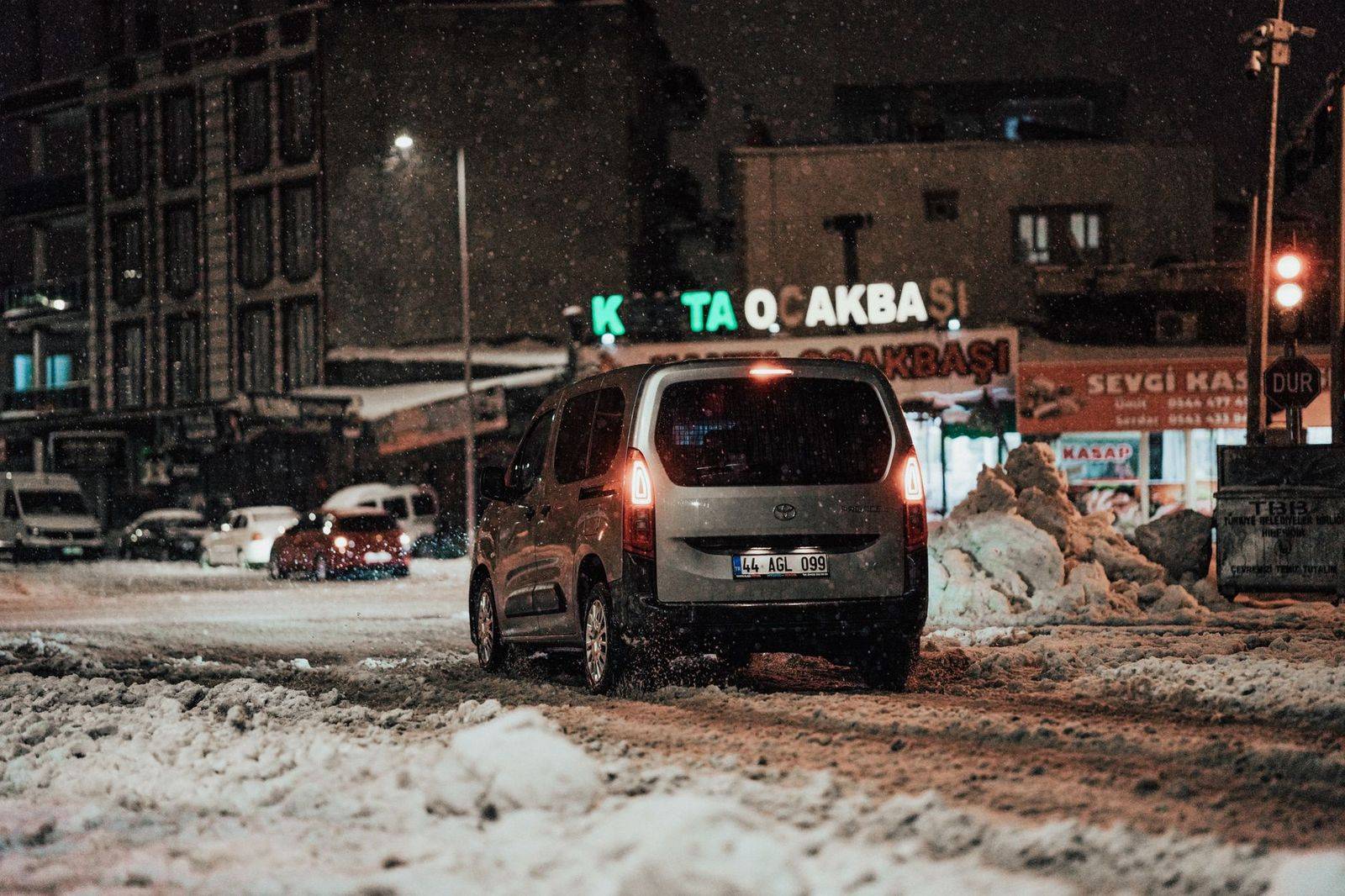 A black sedan waiting on a snowy Toronto street outside a restaurant