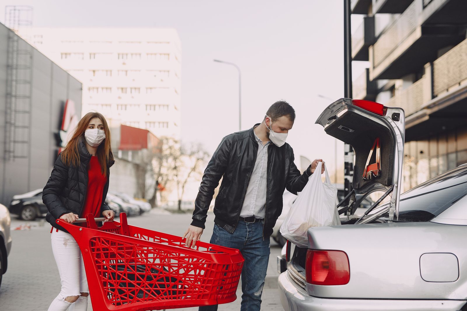 A chauffeur placing shopping bags and a garment bag into the trunk of a black car