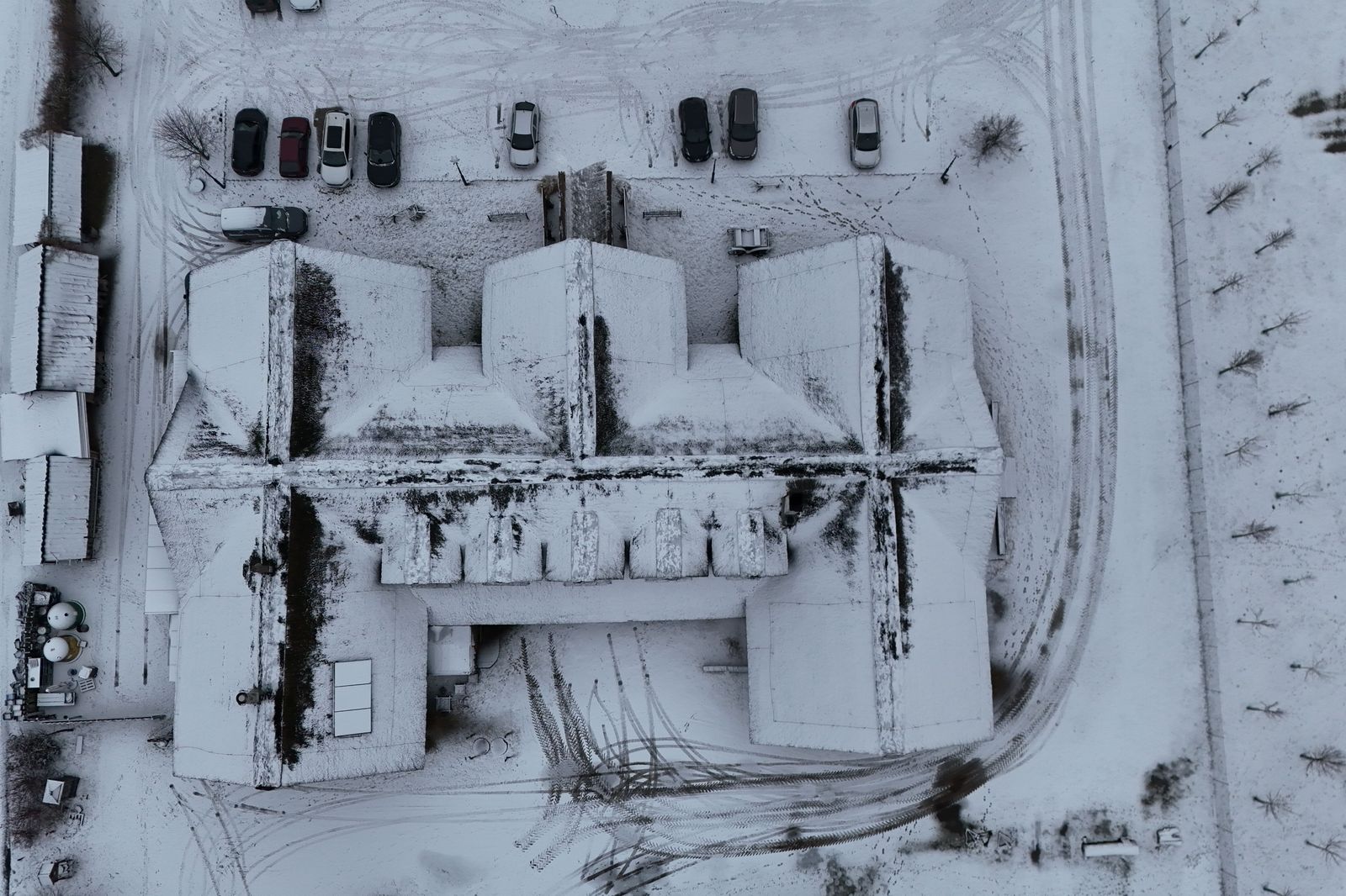 Car covered in snow in an outdoor parking lot after a week away