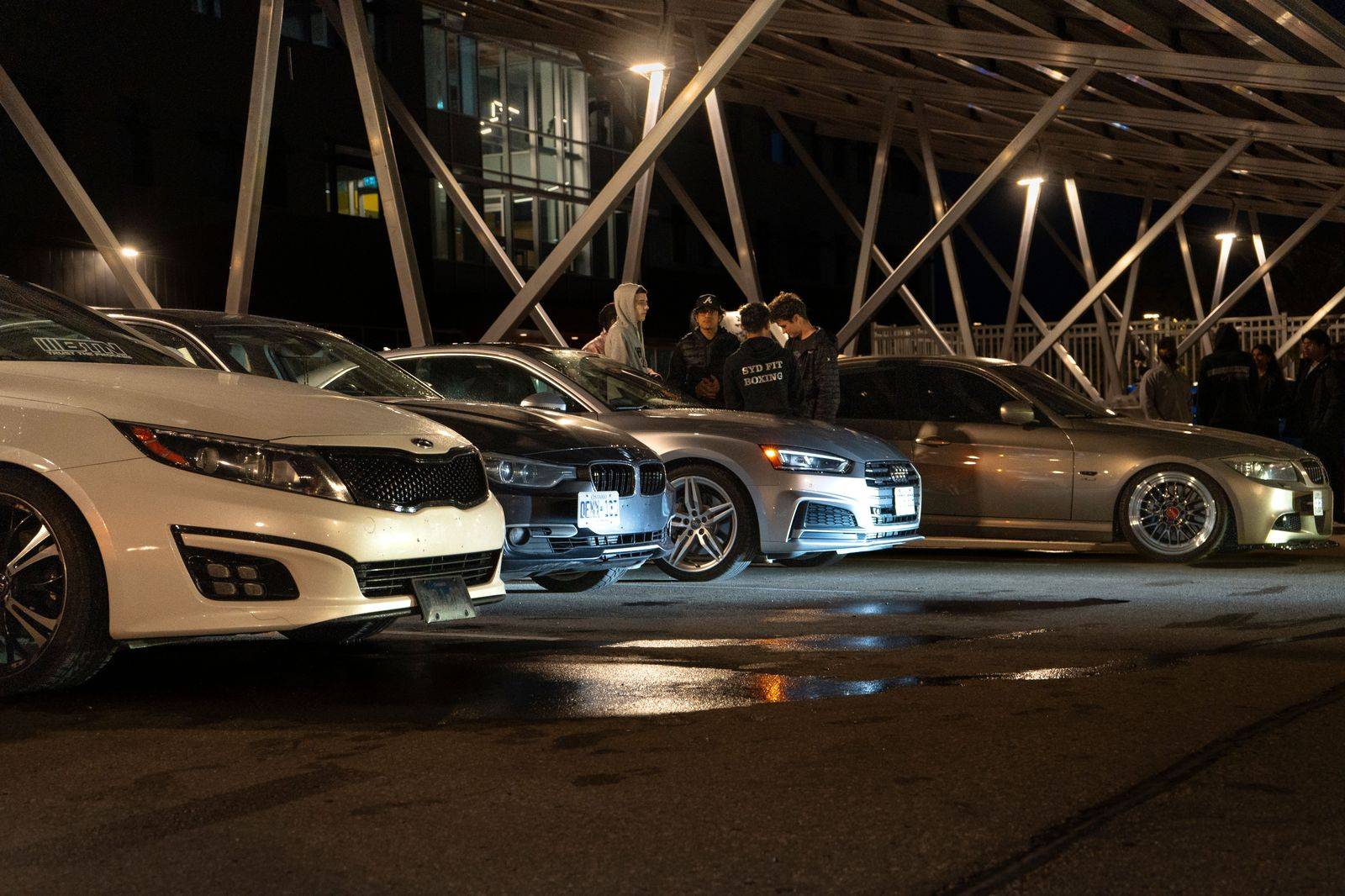 Black sedan waiting at an airport pickup curb at night