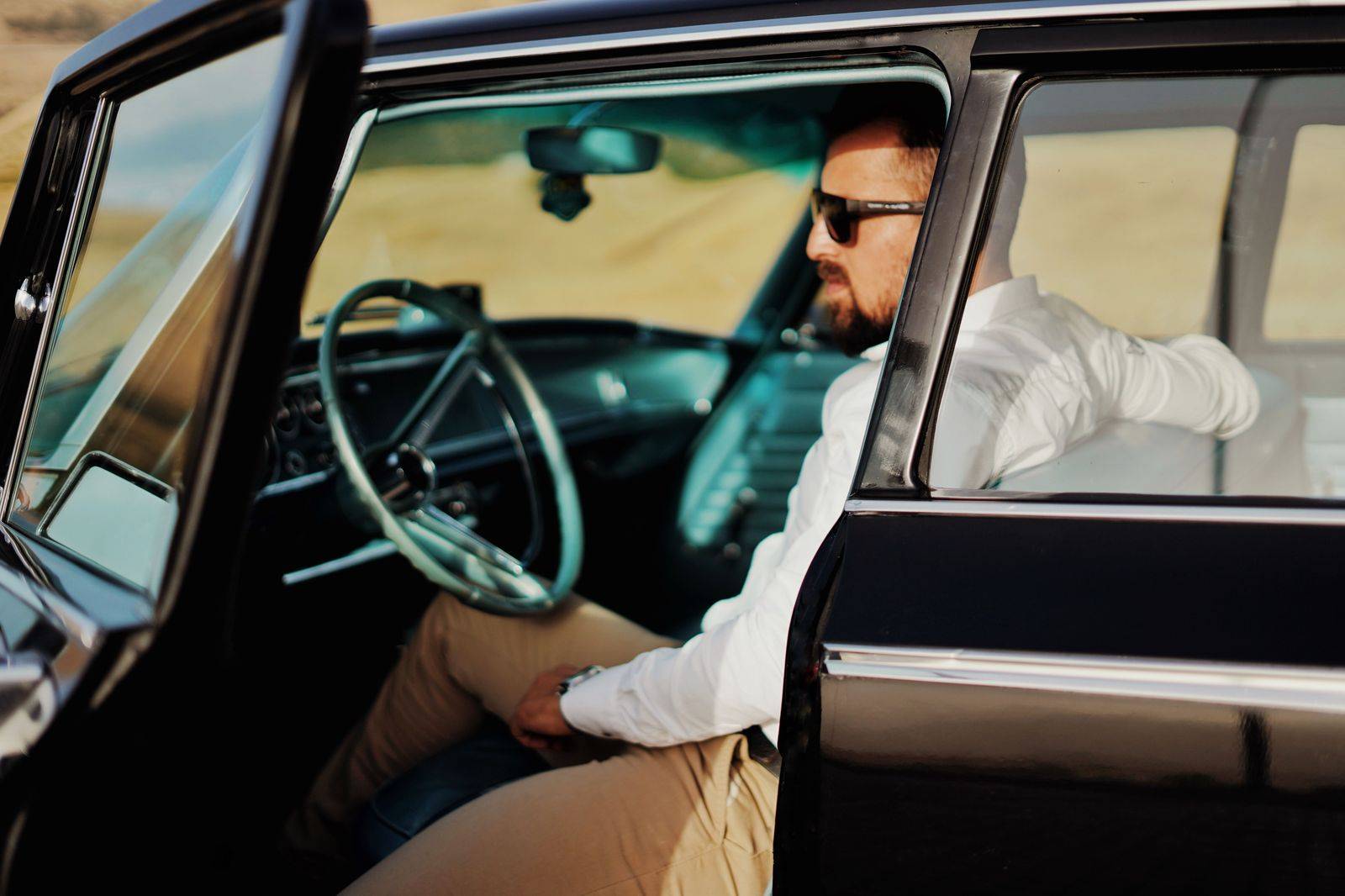 A chauffeur opening the rear door of a black car for guests arriving at a casino entrance