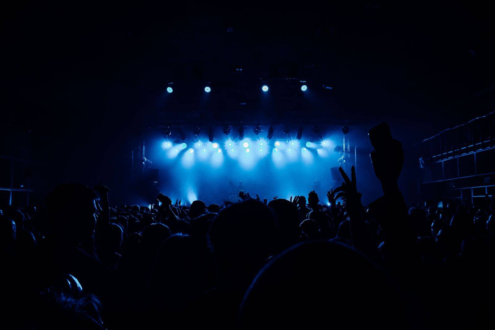 A packed concert venue with stage lights, the kind of night that suits a chauffeur waiting outside